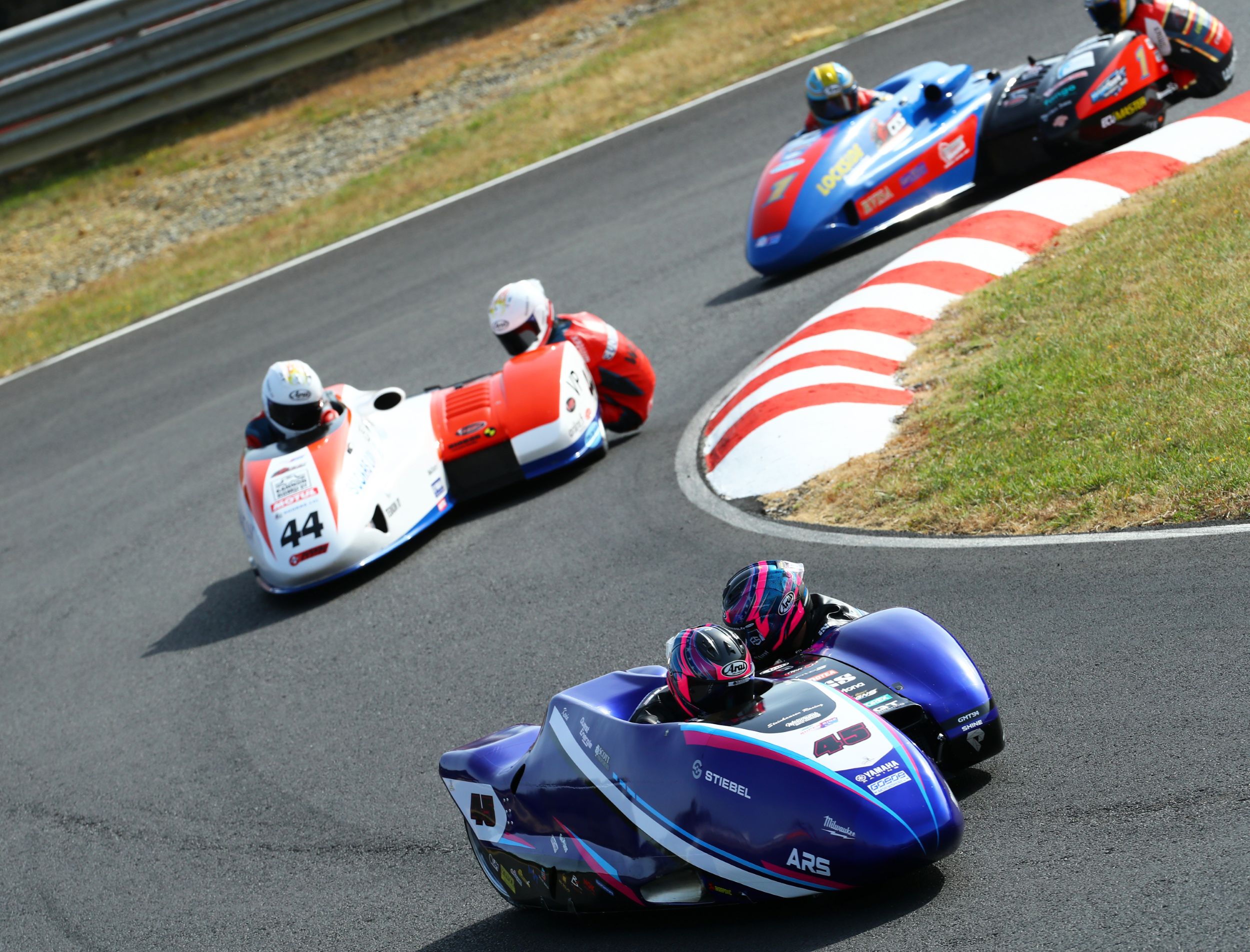Motorbike sidecar racing on a curved track with riders leaning