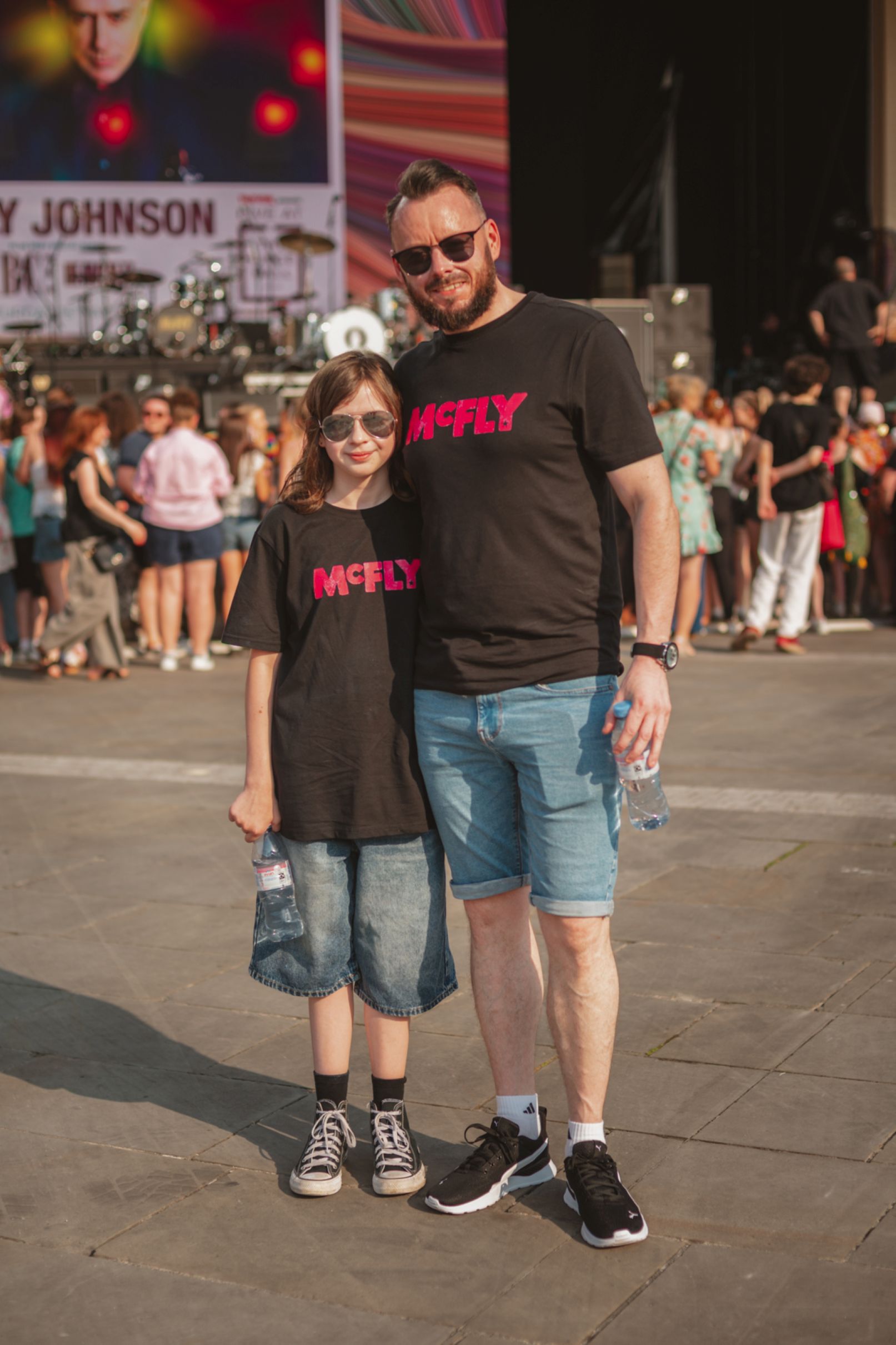 Father and child in matching shirts at outdoor concert