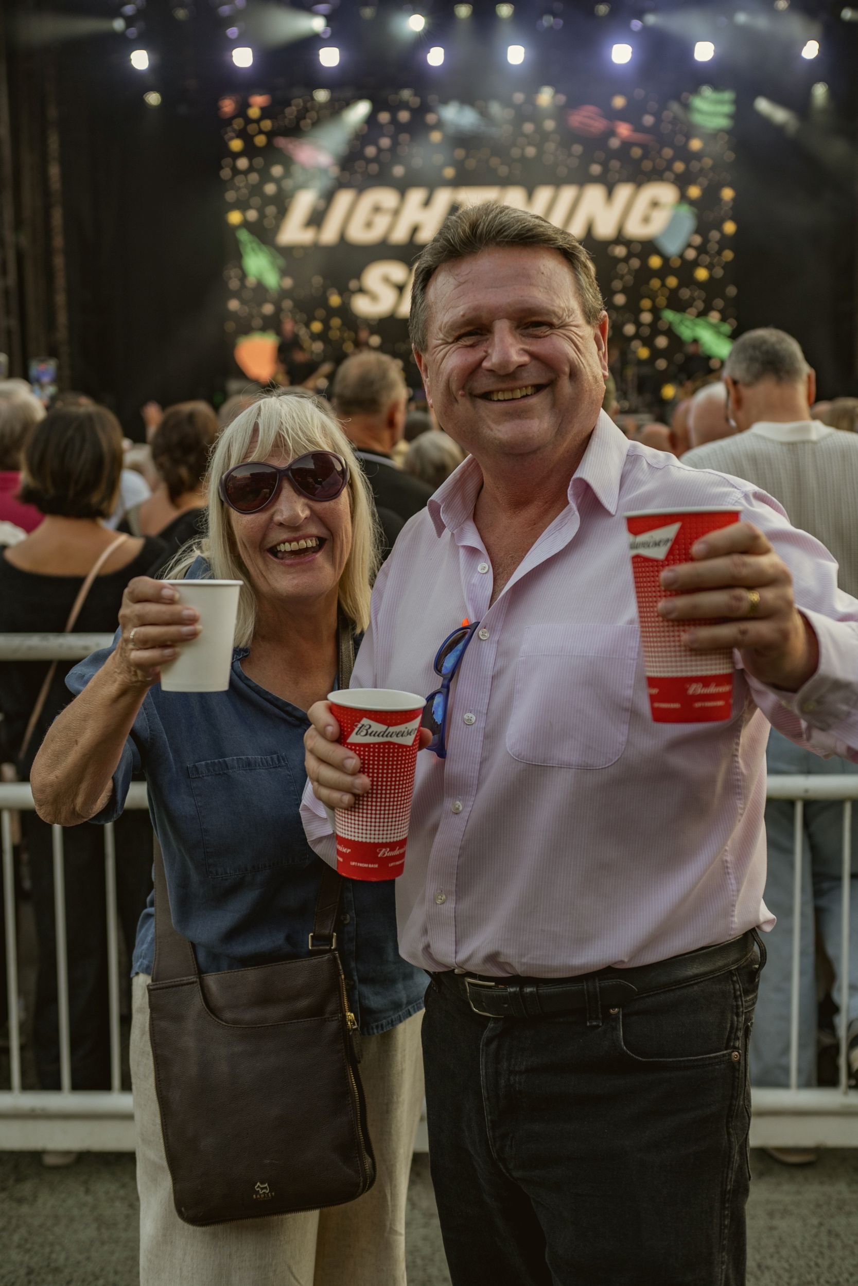 Smiling couple holding drinks at an outdoor music festival