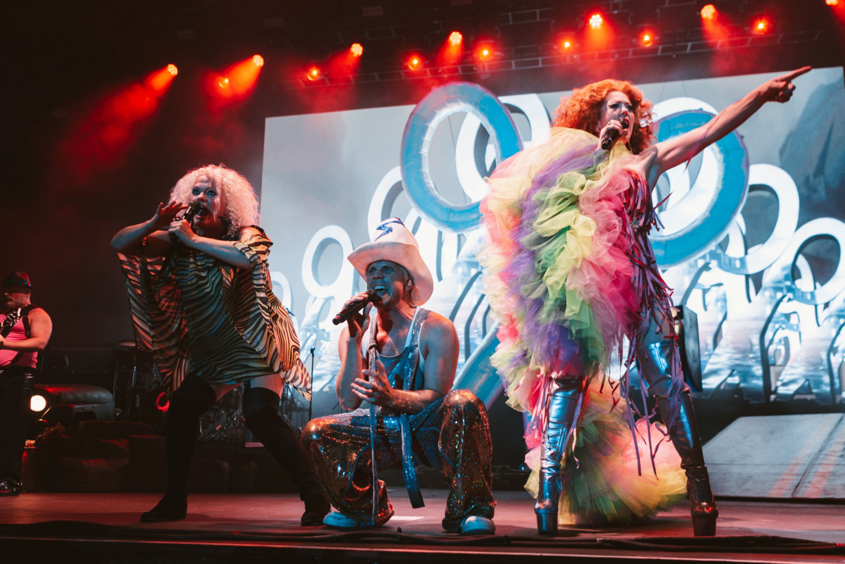 Vibrant drag performers in colourful costumes on stage with lights