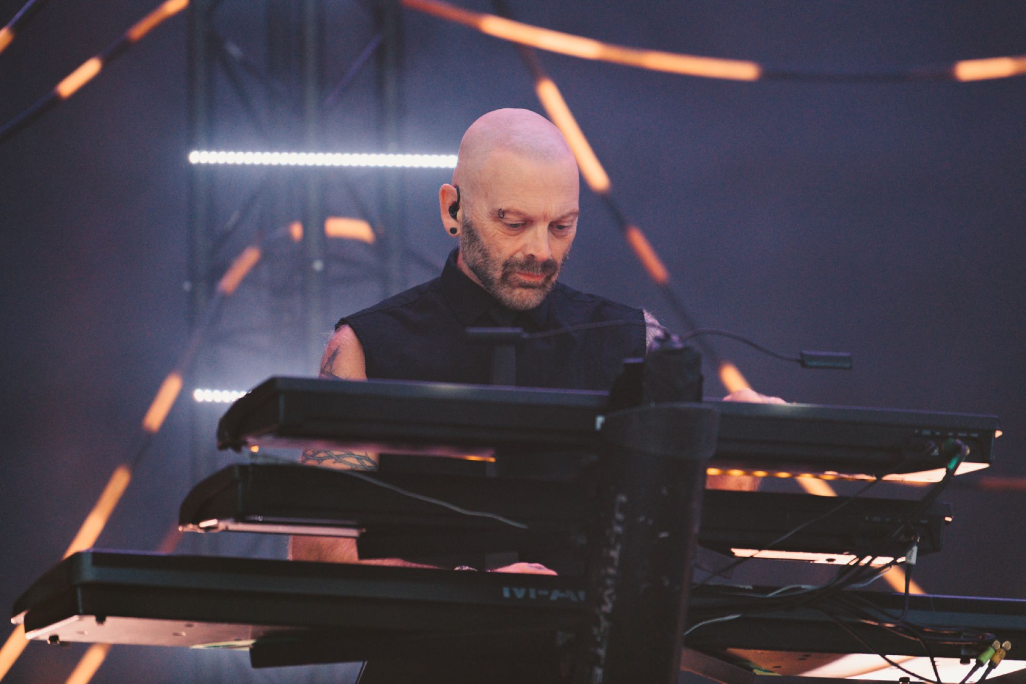 Musician playing keyboard on stage with dramatic lighting