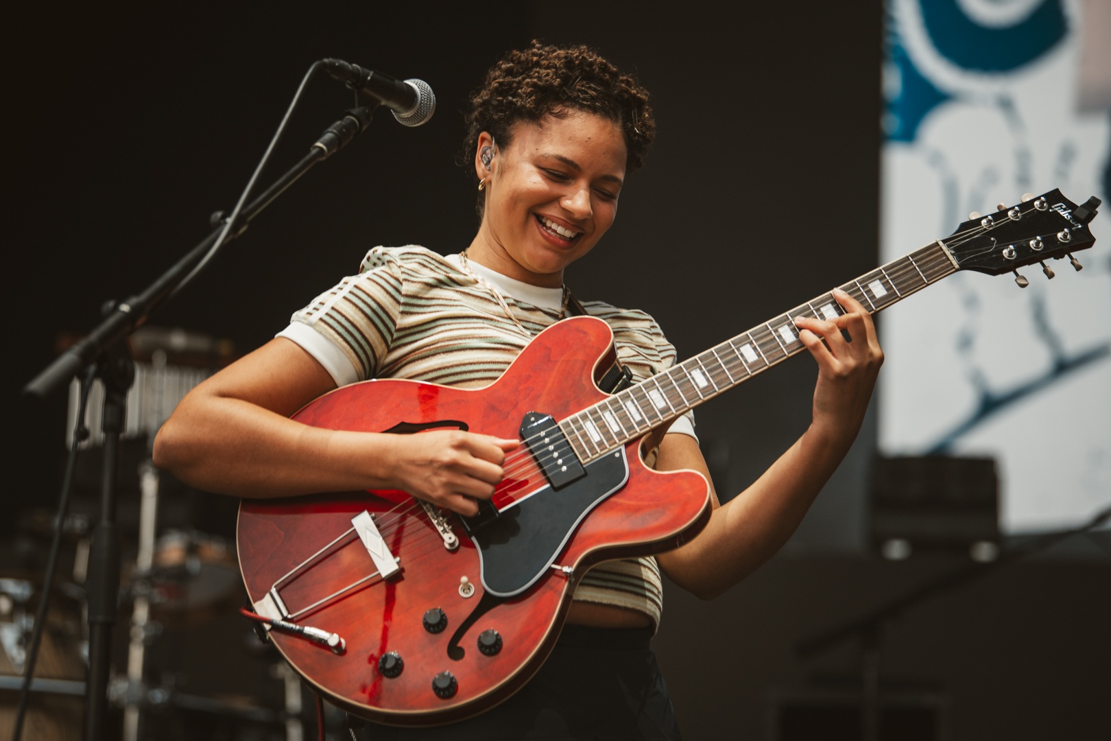 Smiling musician playing a red electric guitar on stage