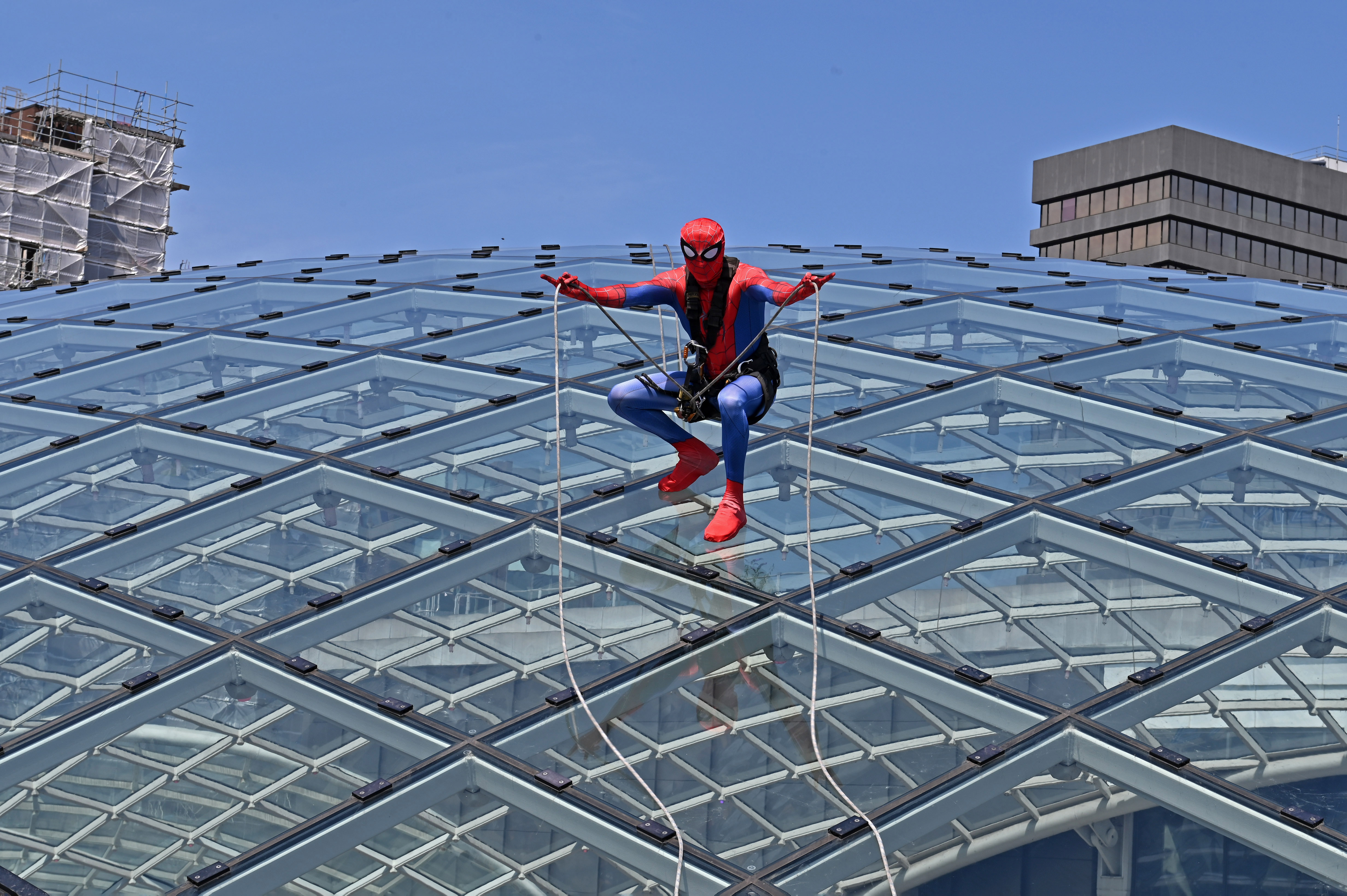 Person in superhero costume climbing glass domed roof