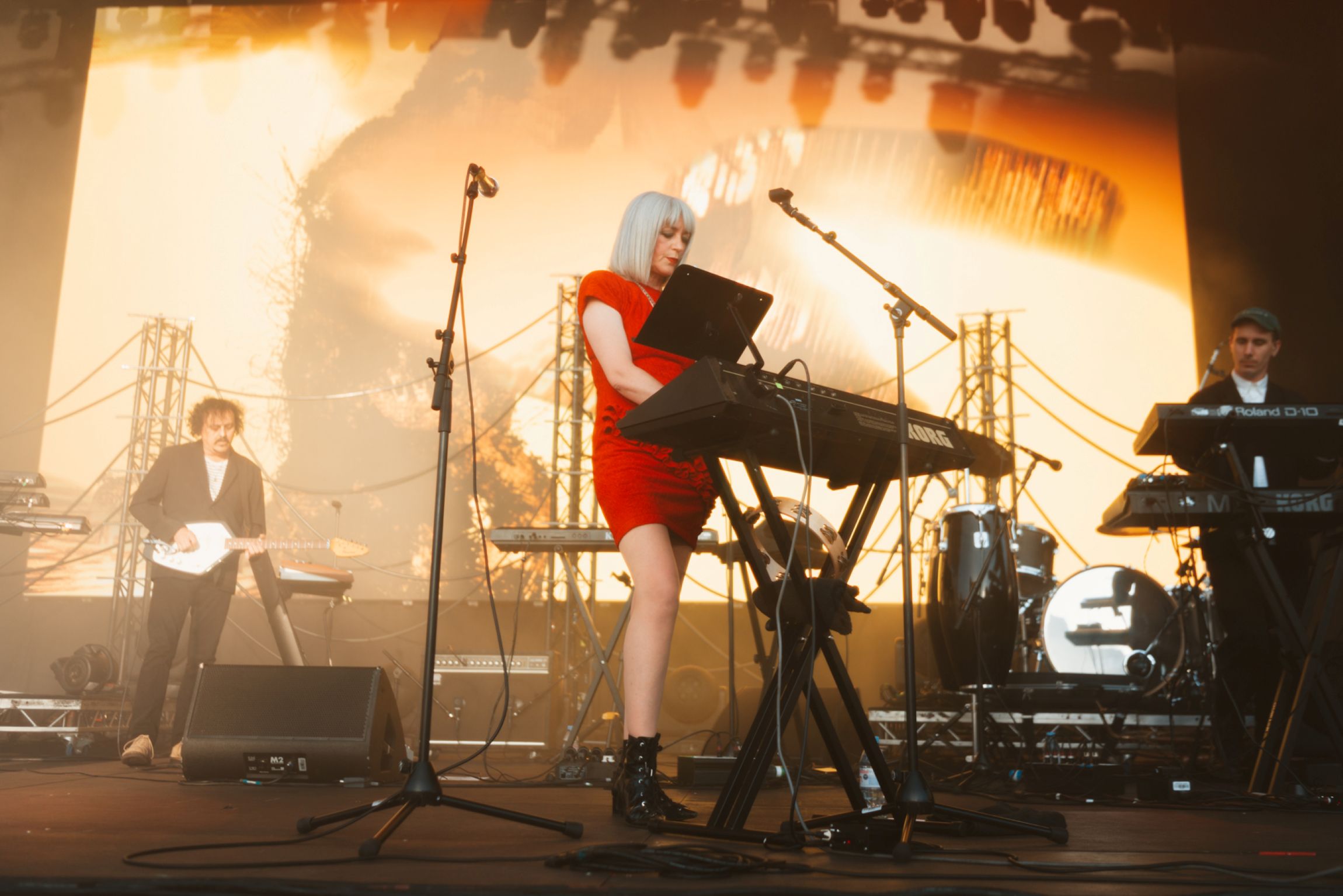 Band performing on stage with a vibrant orange backdrop