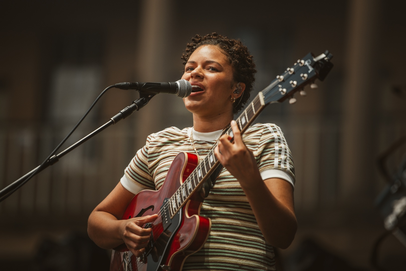 Musician playing red guitar and singing on outdoor stage