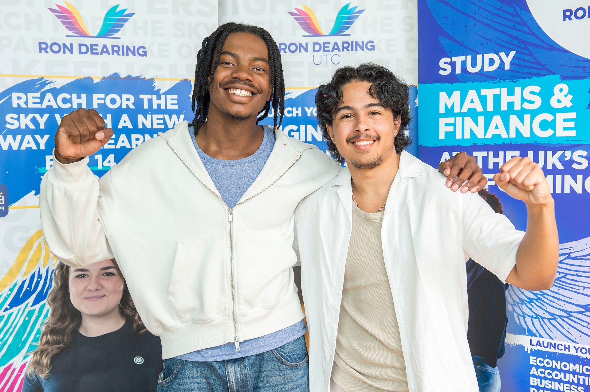 Two smiling students with promotional banners in background