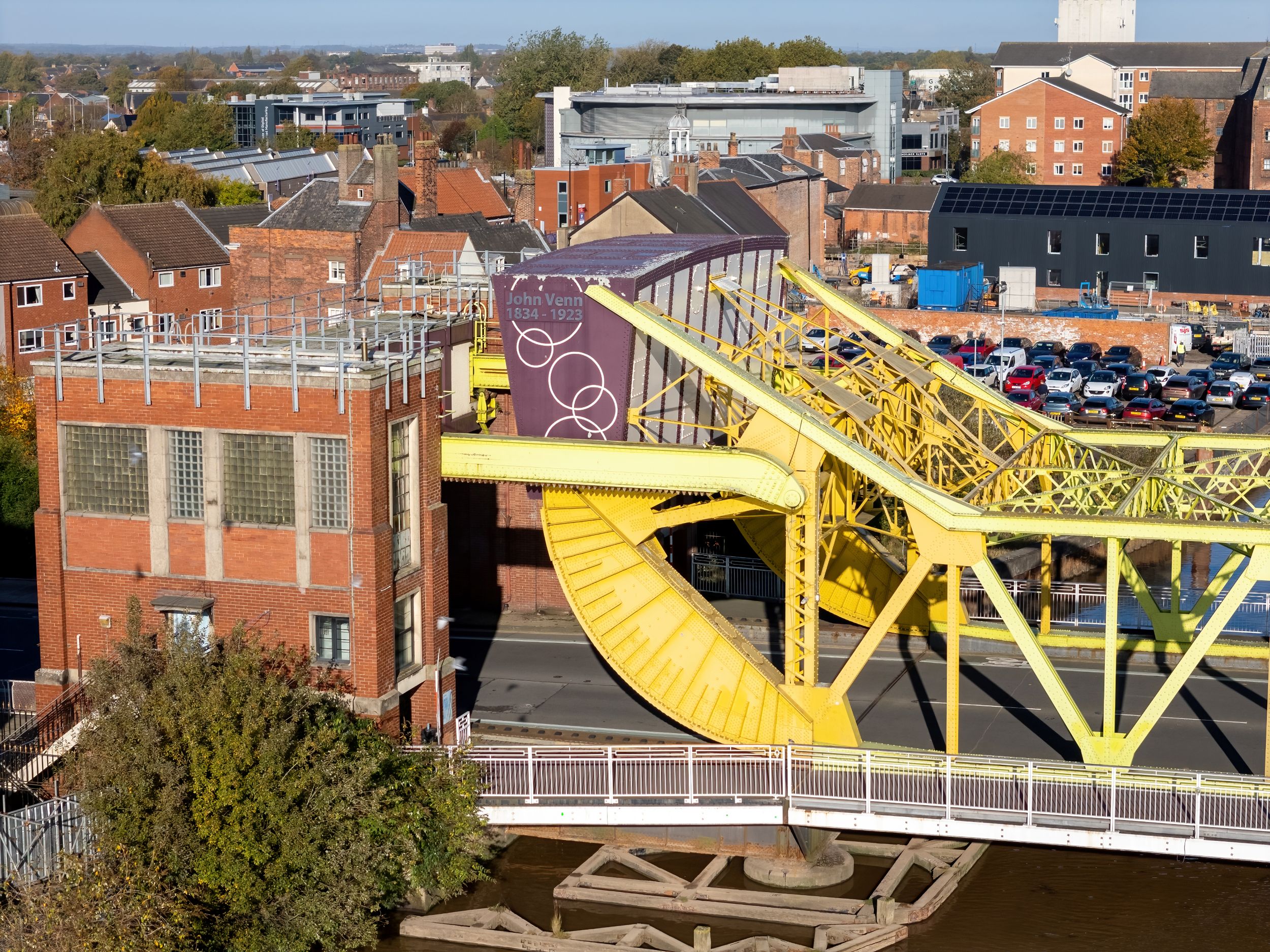 Bright yellow swing bridge over a canal in an urban setting