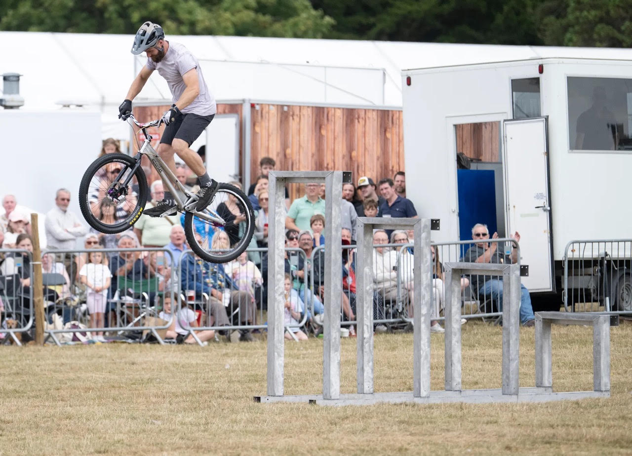 Cyclist performing a stunt jump over metal obstacles at outdoor event