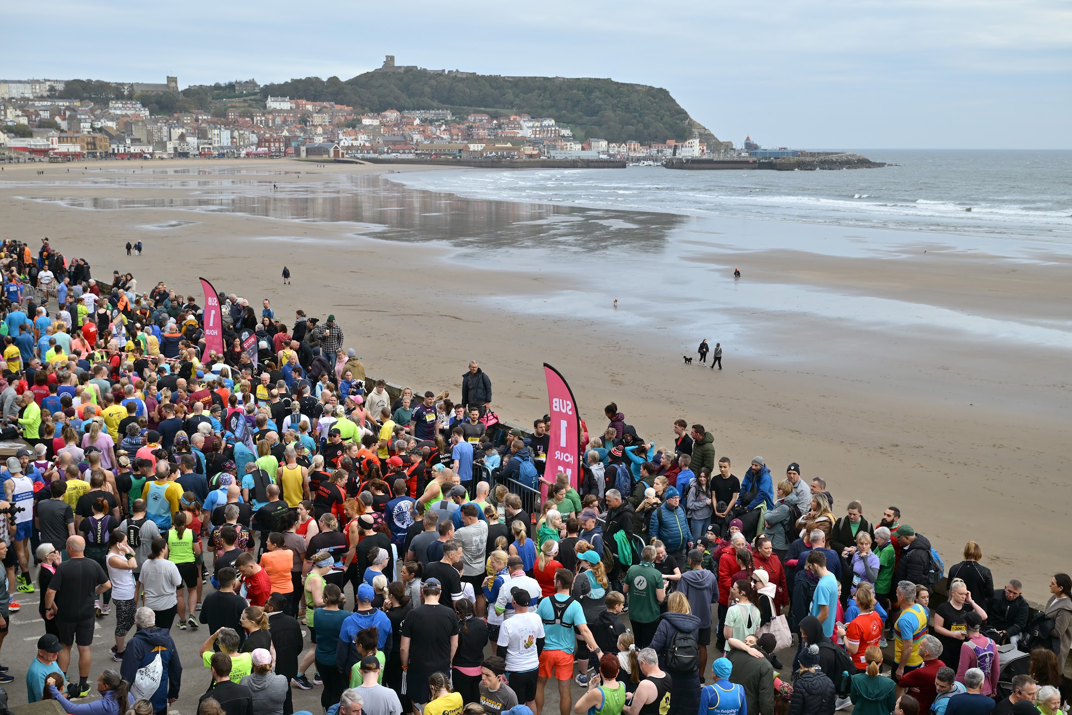Crowd of runners on Scarborough beach with town and cliffs