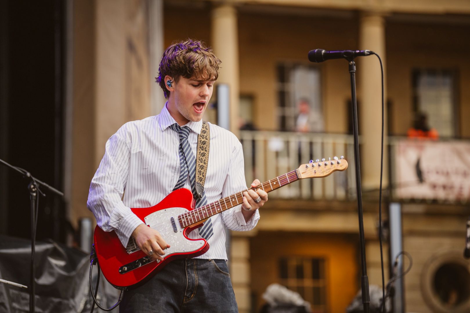Musician playing red electric guitar on outdoor stage