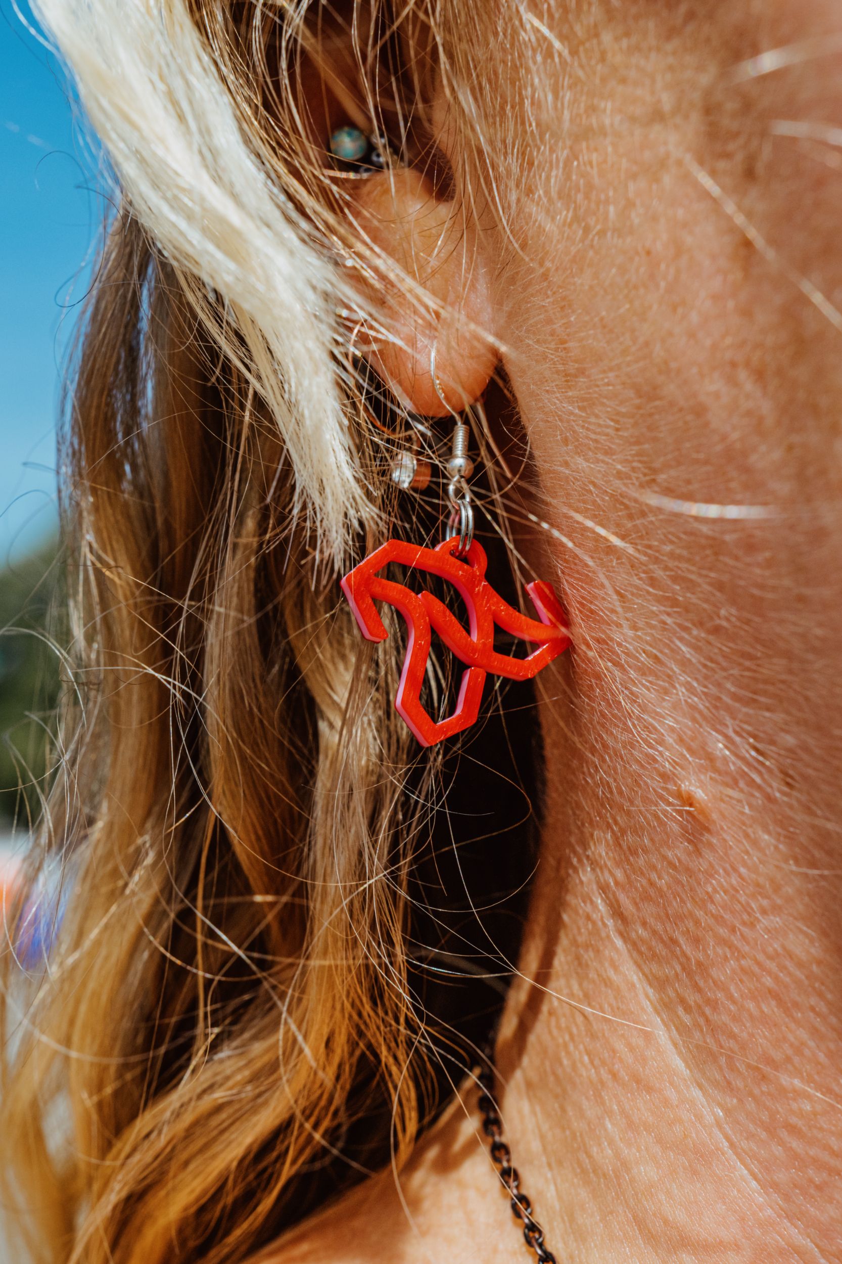 Close-up of a person wearing red geometric earrings