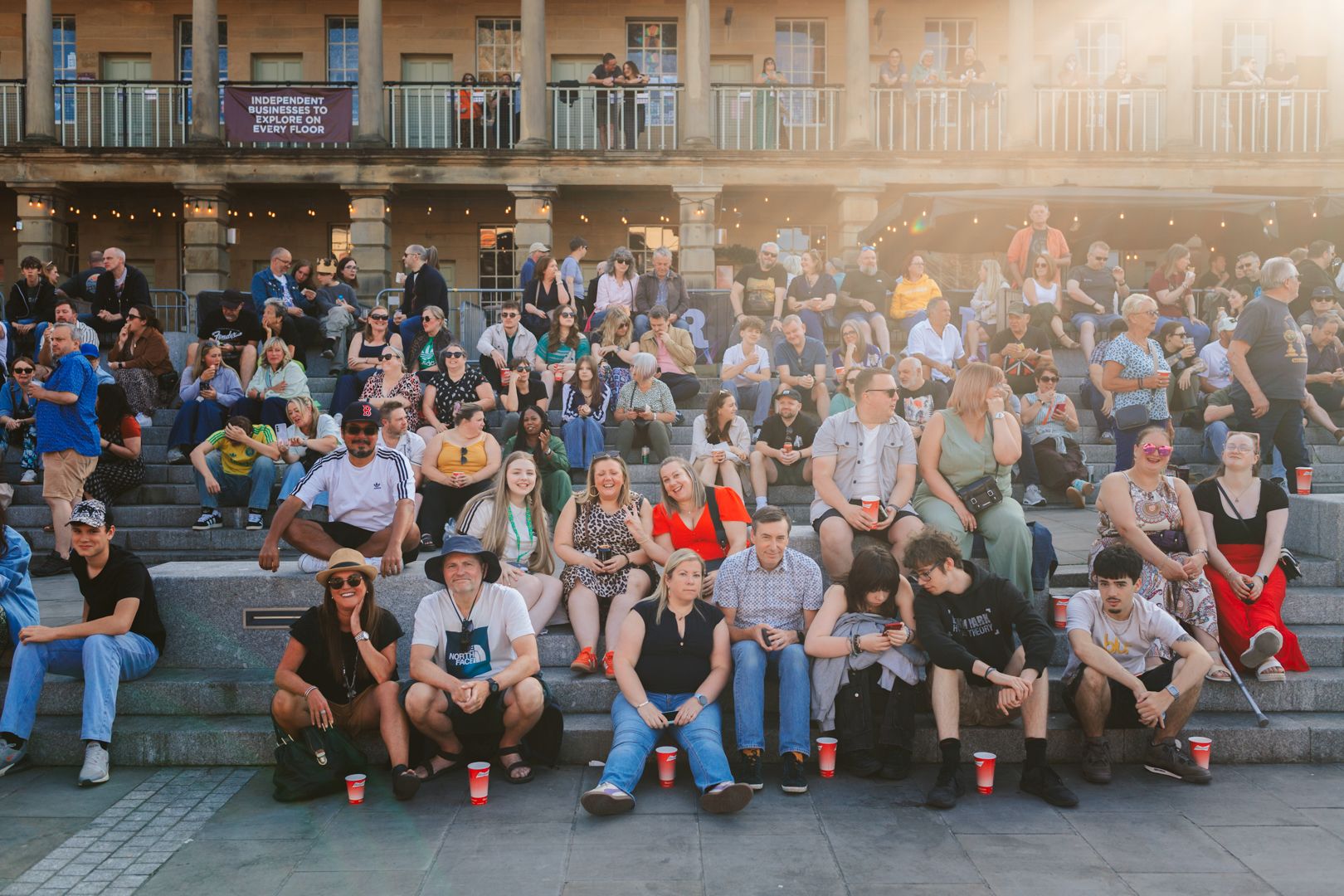 Crowd of people sitting on steps enjoying sunny day in city square