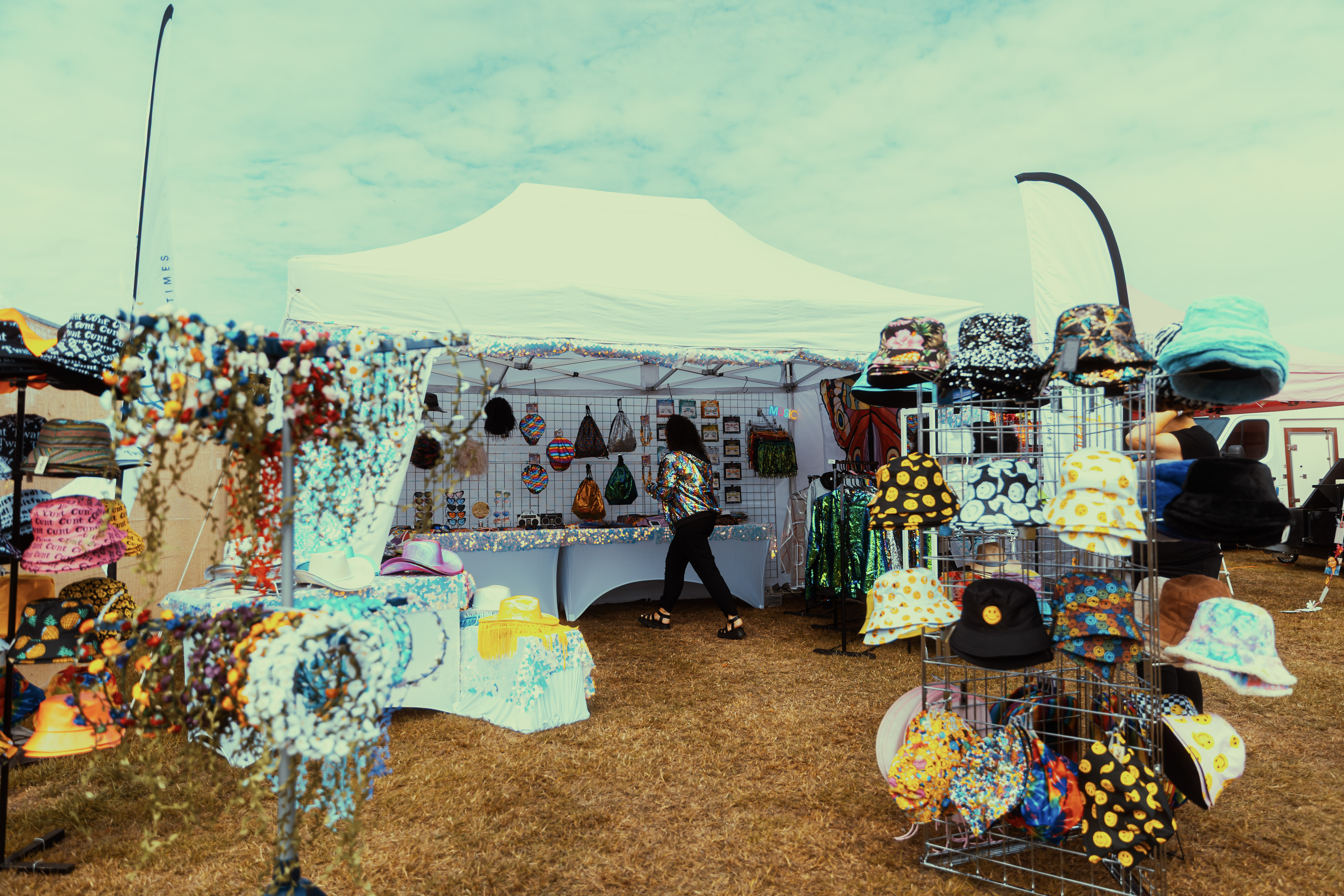 Colorful outdoor market stall with hats and jewelry under a tent