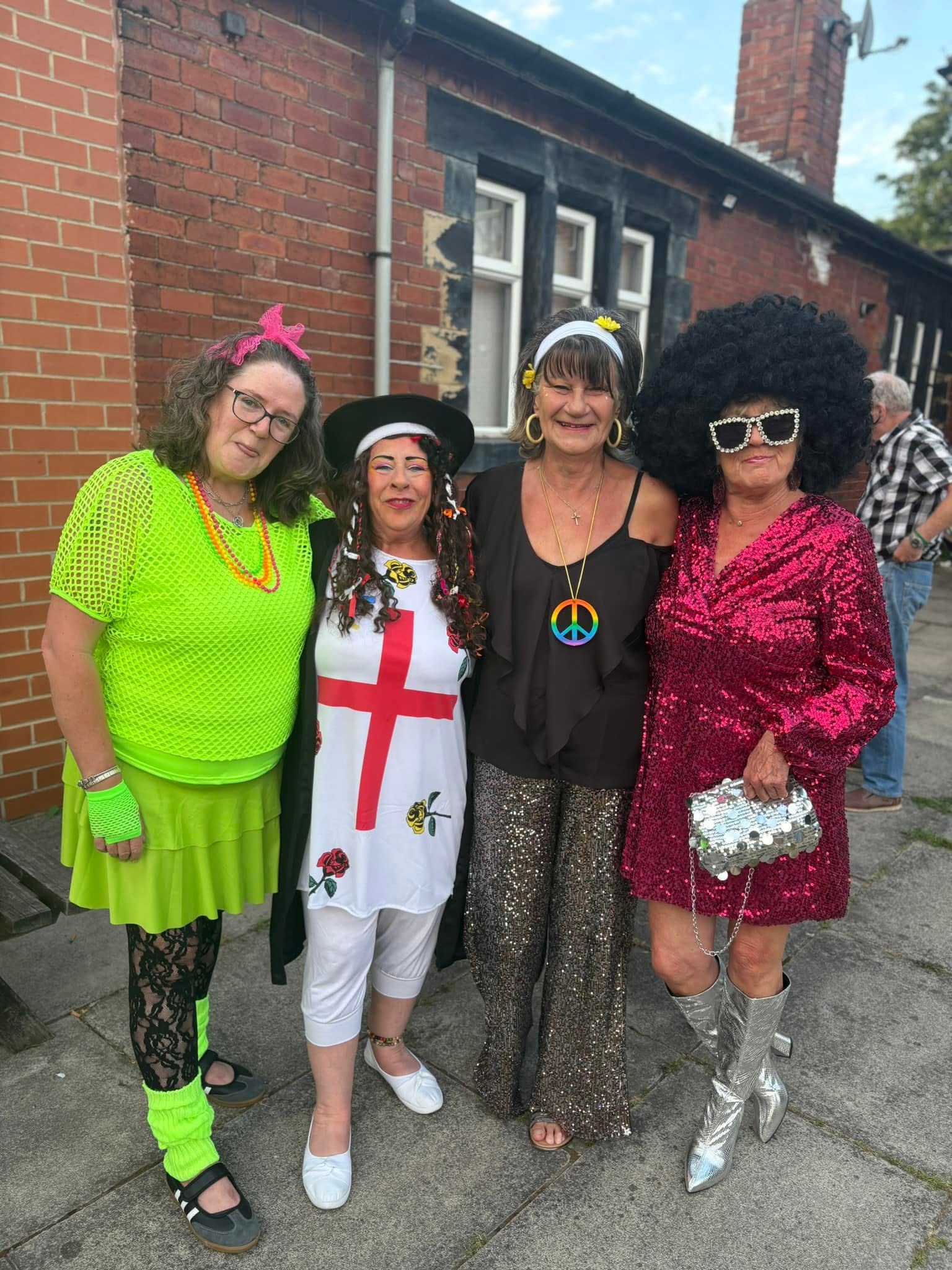 Four people in colourful, themed costumes standing together