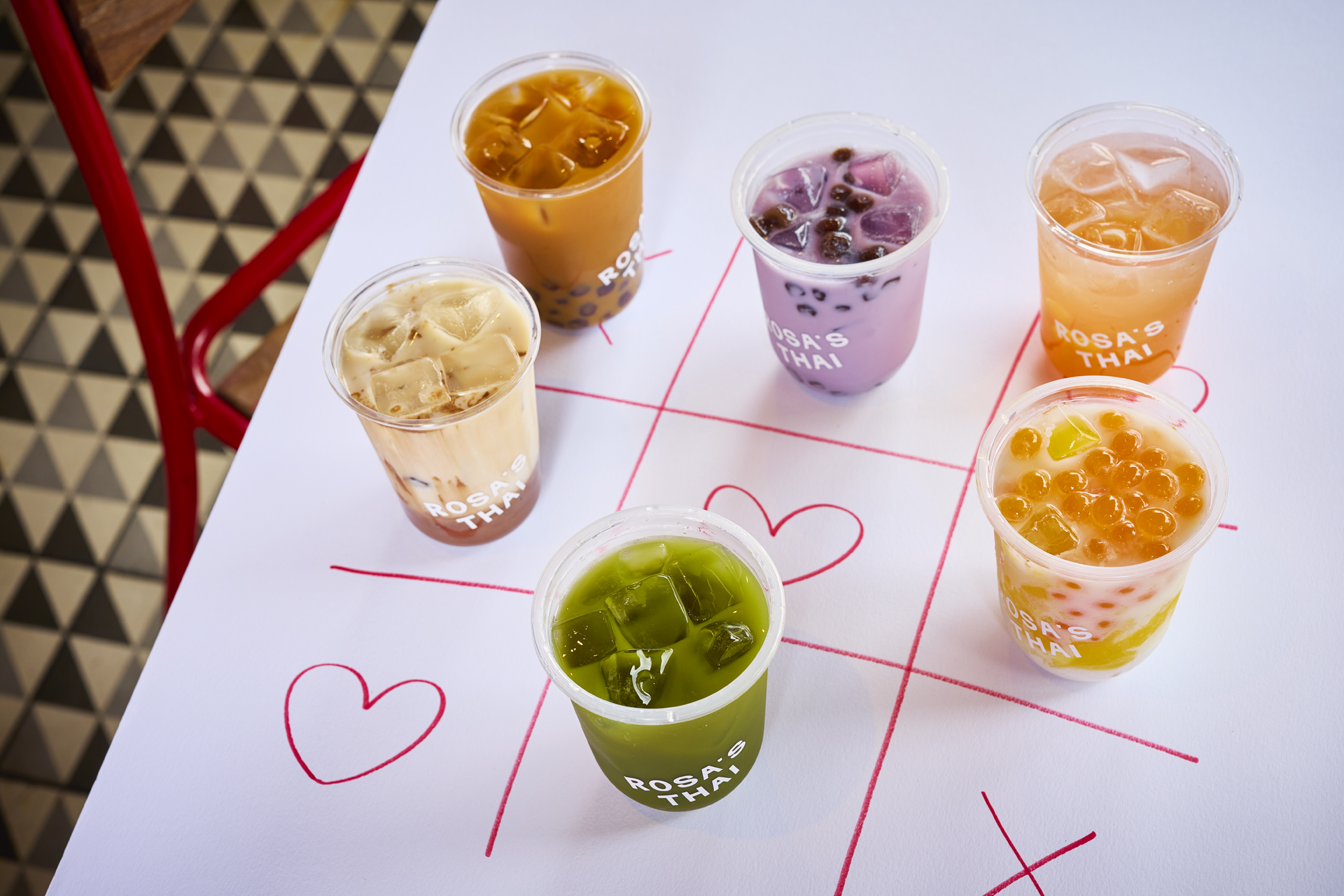 Assorted bubble teas on tic-tac-toe board with hearts