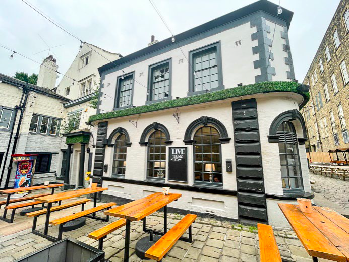 Charming pub with black and white facade, outdoor seating on cobblestones