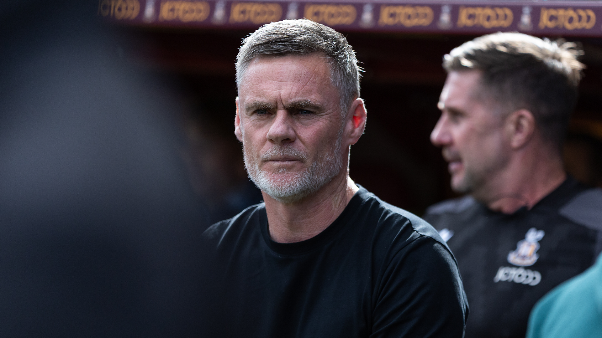 Man with grey beard in black shirt at outdoor event