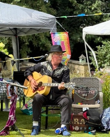 Musician in black hat playing acoustic guitar in garden