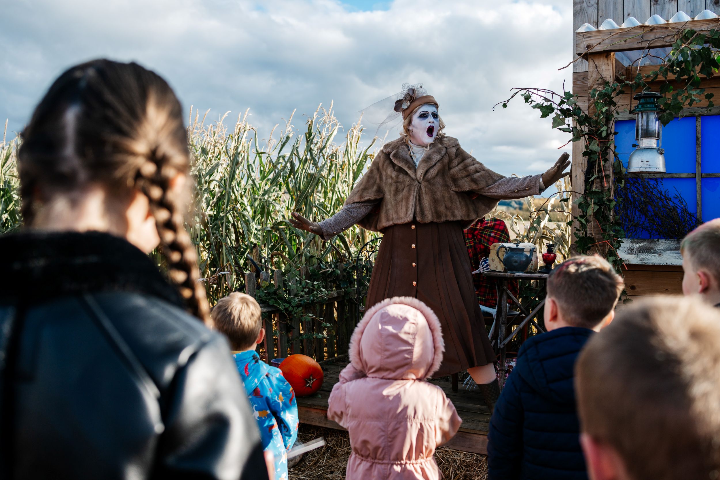 Performer in vintage outfit entertaining children at a pumpkin patch