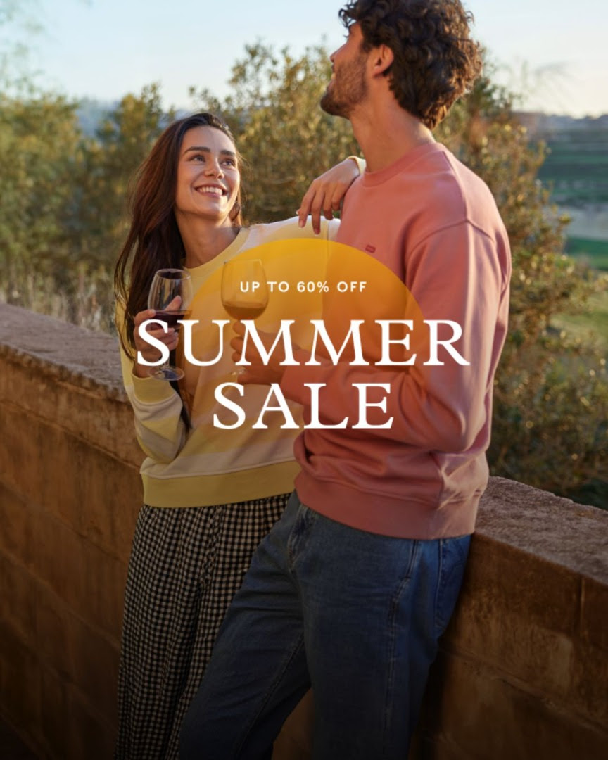 Couple in casual attire enjoying view over stone wall