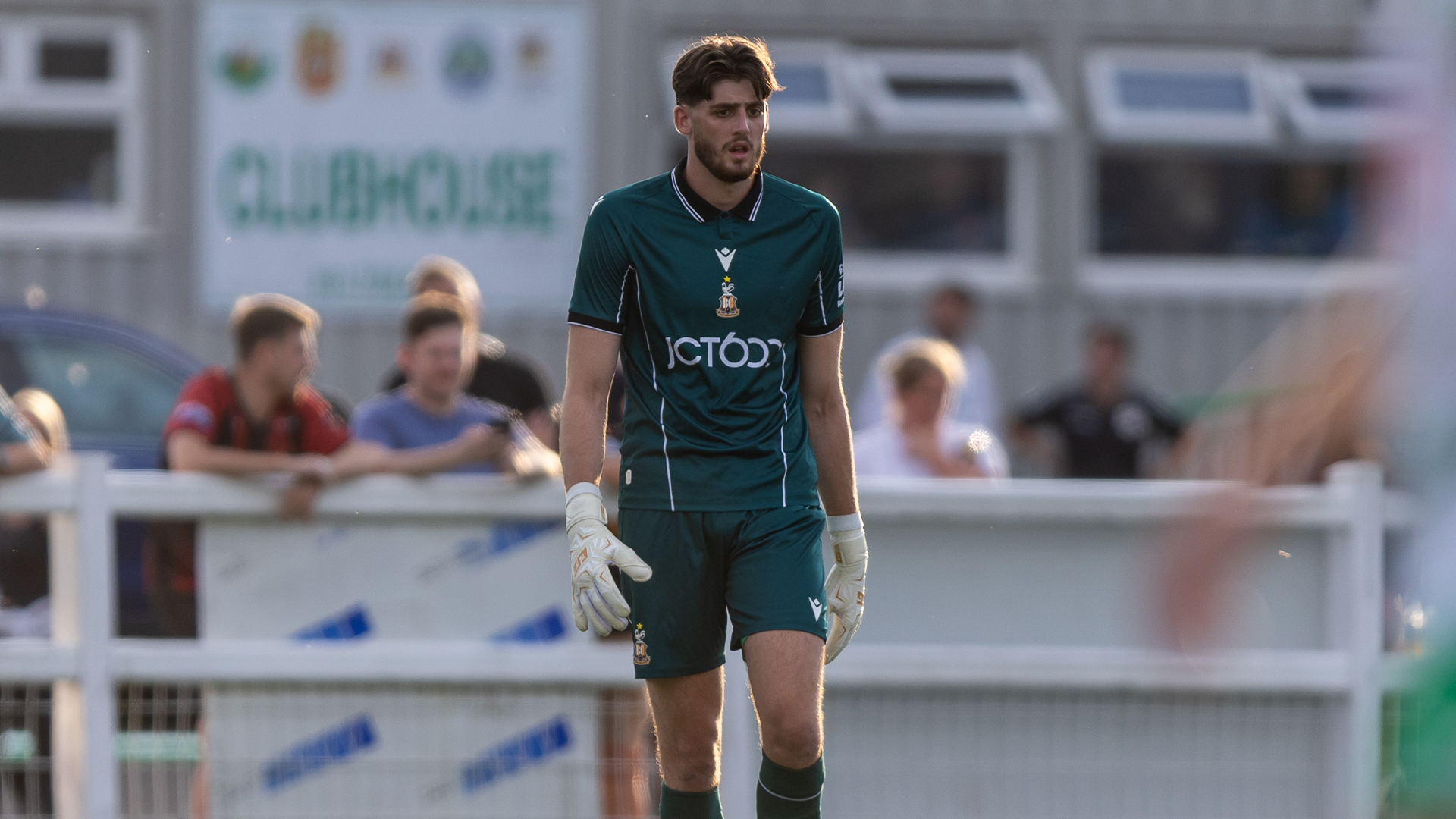 Football goalkeeper in green kit walking on pitch during a match