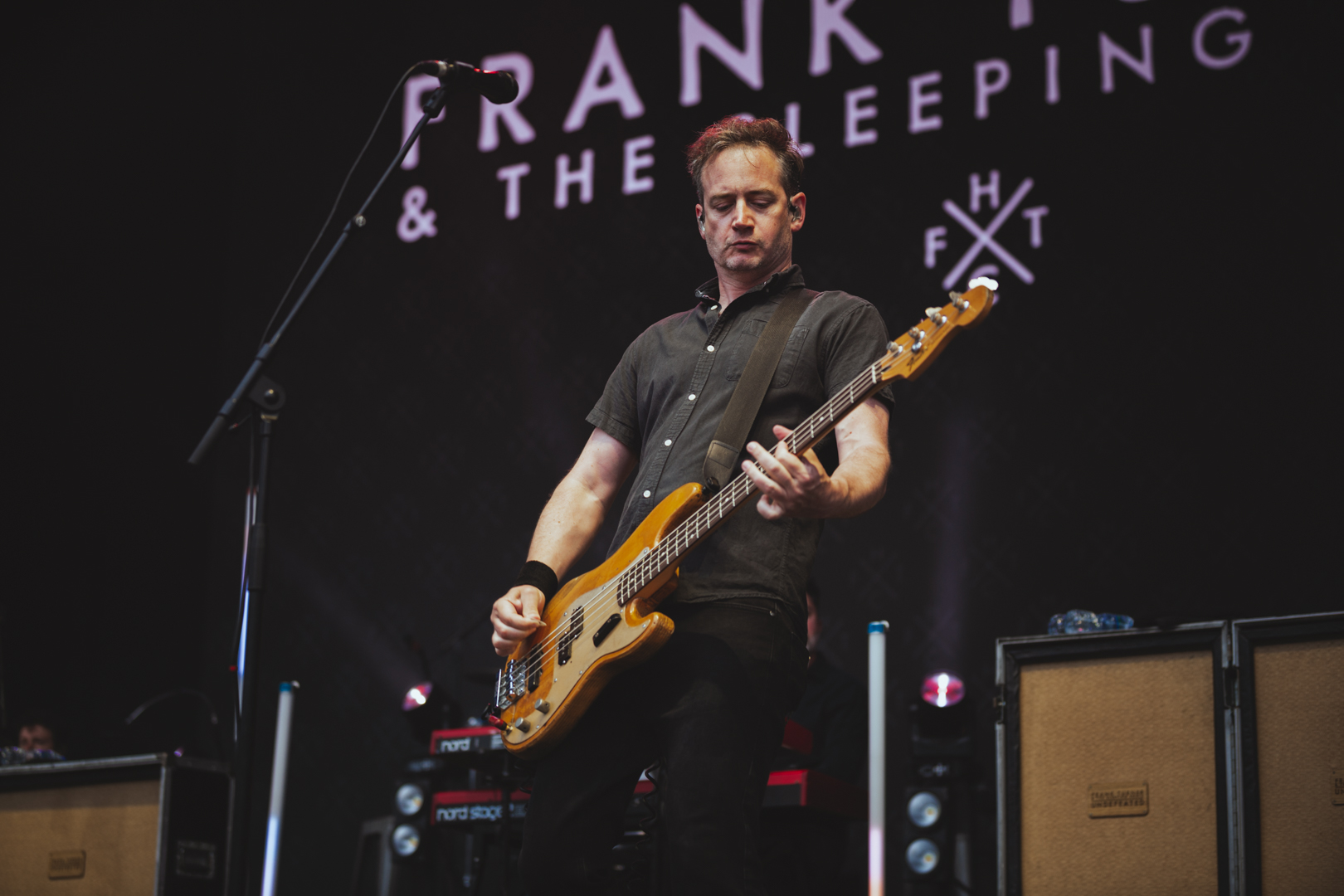 Musician playing electric guitar on stage with dark backdrop