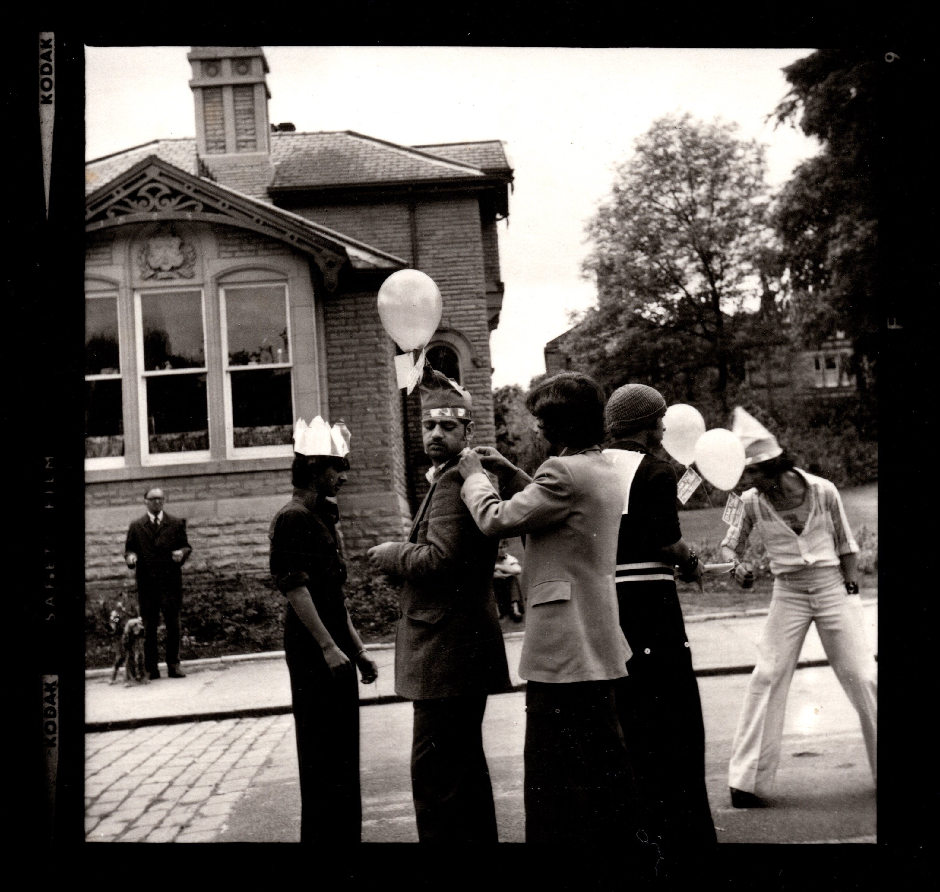 Group of people with balloons at a street party near stone building