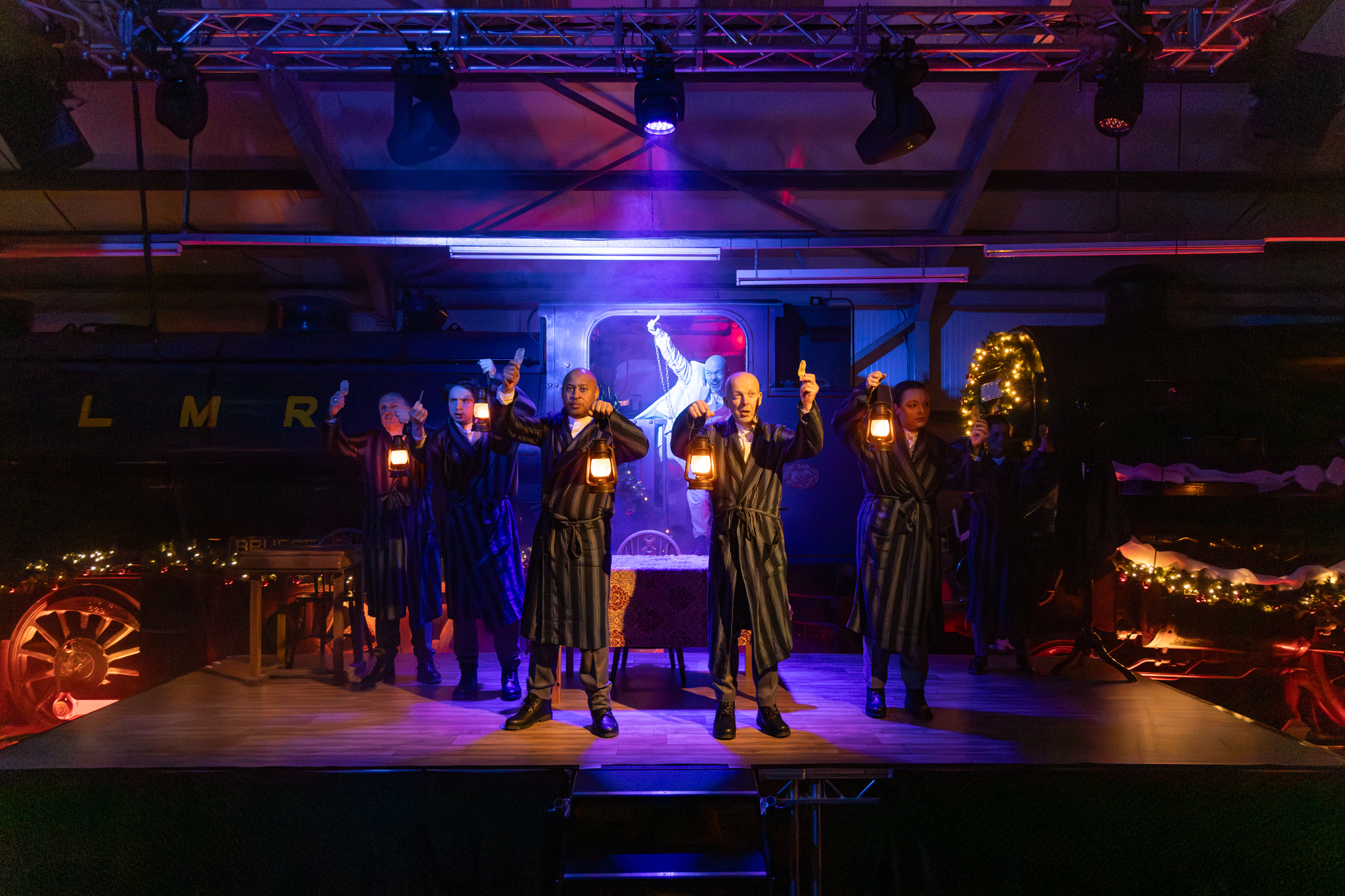 Performers in striped robes holding lanterns on a lit stage