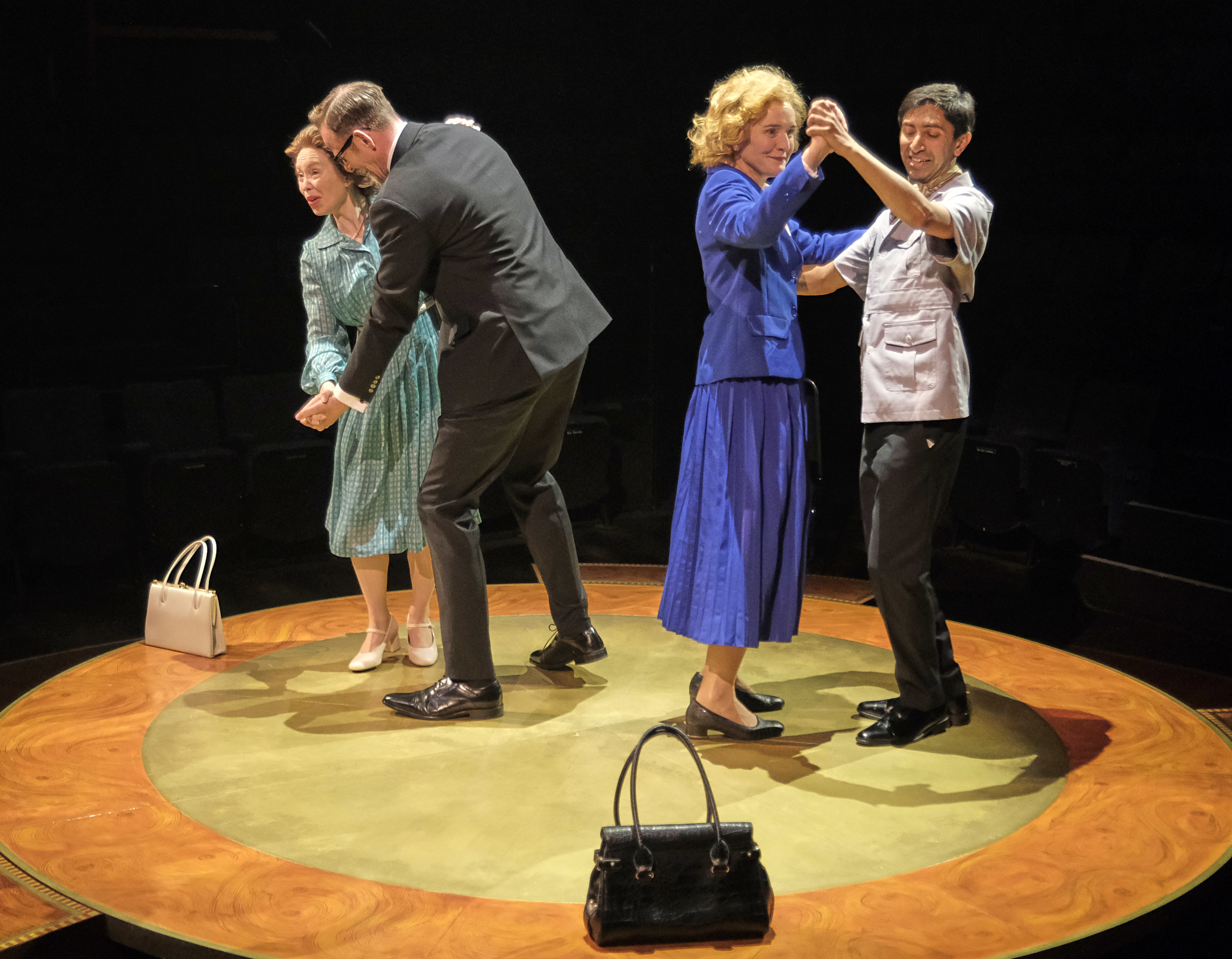 Four people in vintage attire dancing on a circular stage