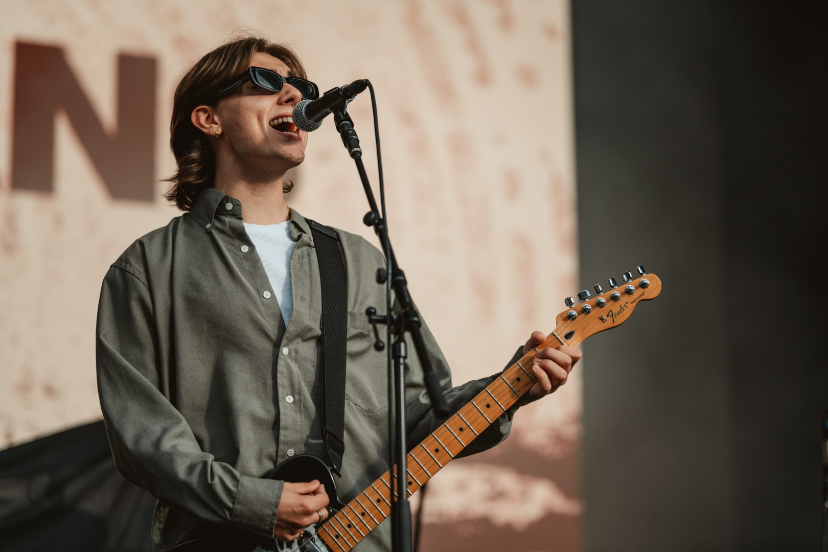 Musician wearing sunglasses playing guitar and singing on stage