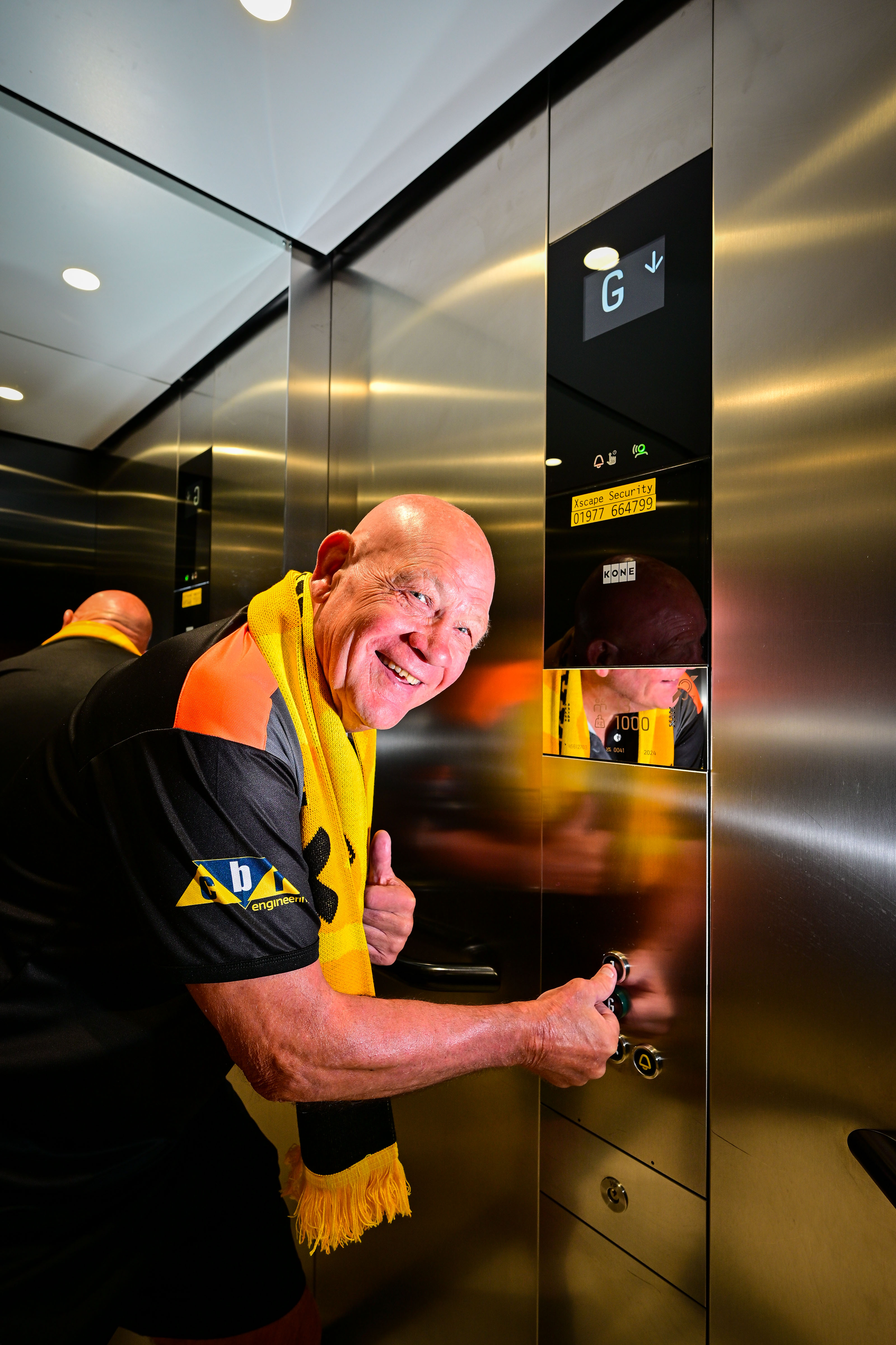 Smiling elderly man in football attire with scarf in lift