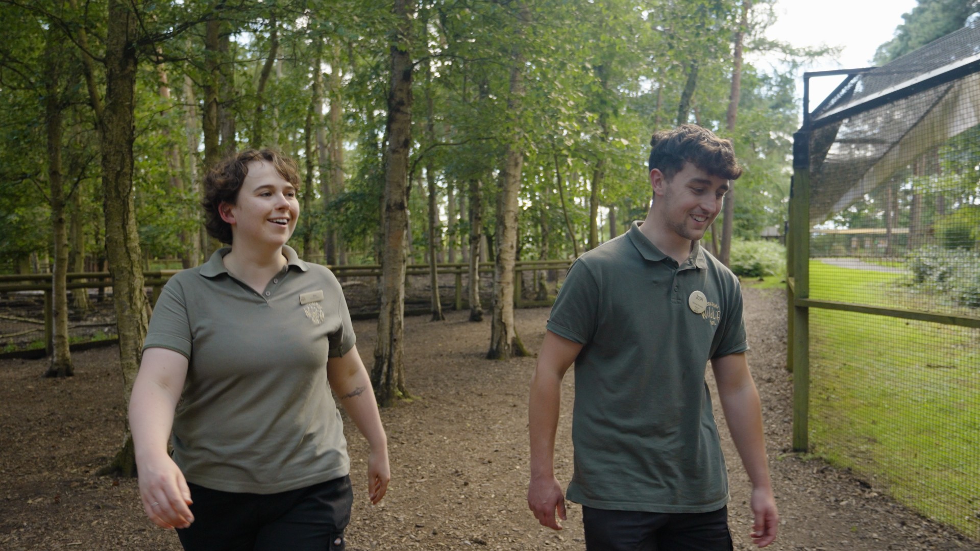Two park rangers walking along a wooded path in summer