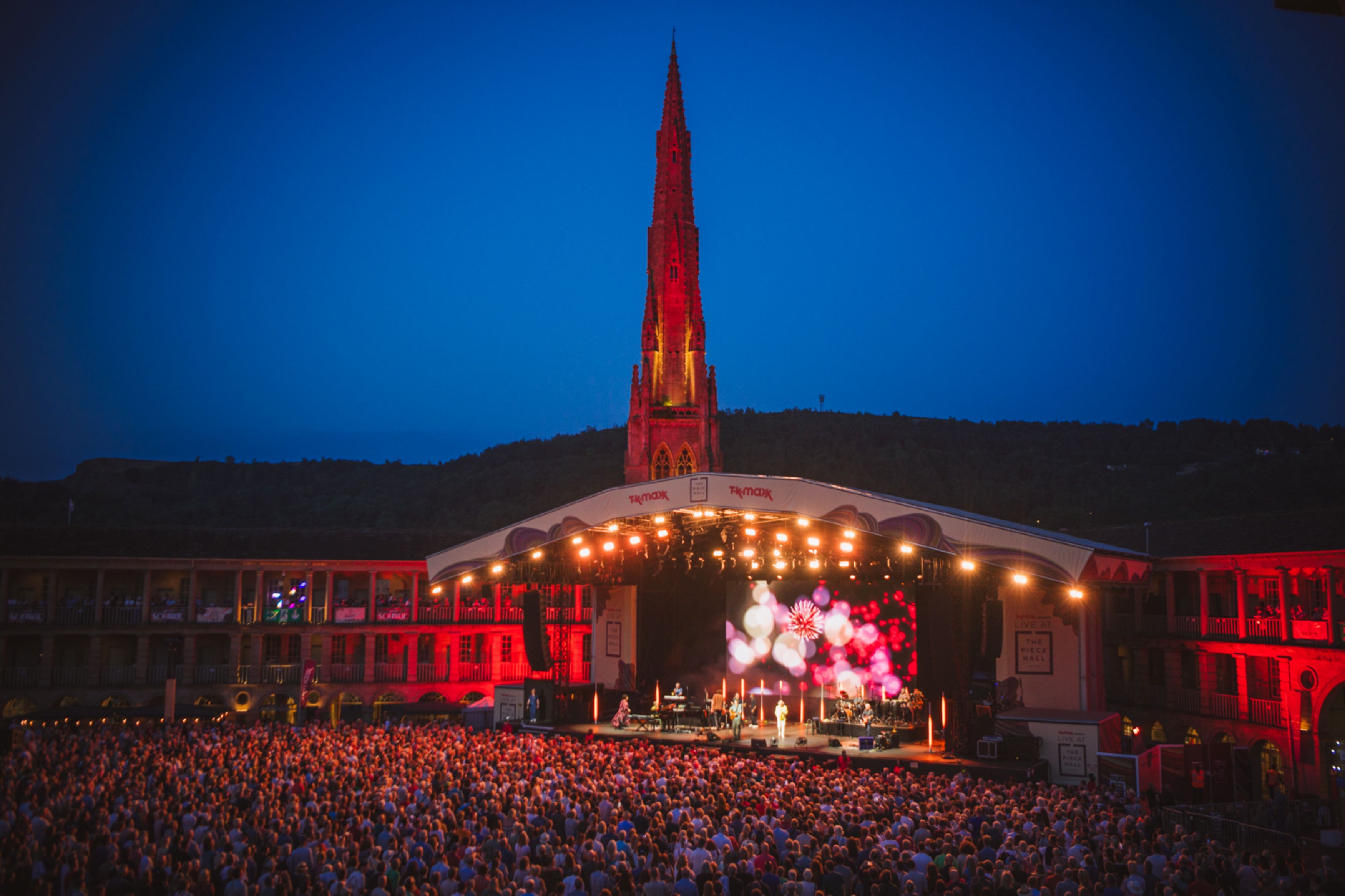 Evening concert at open-air venue with illuminated spire