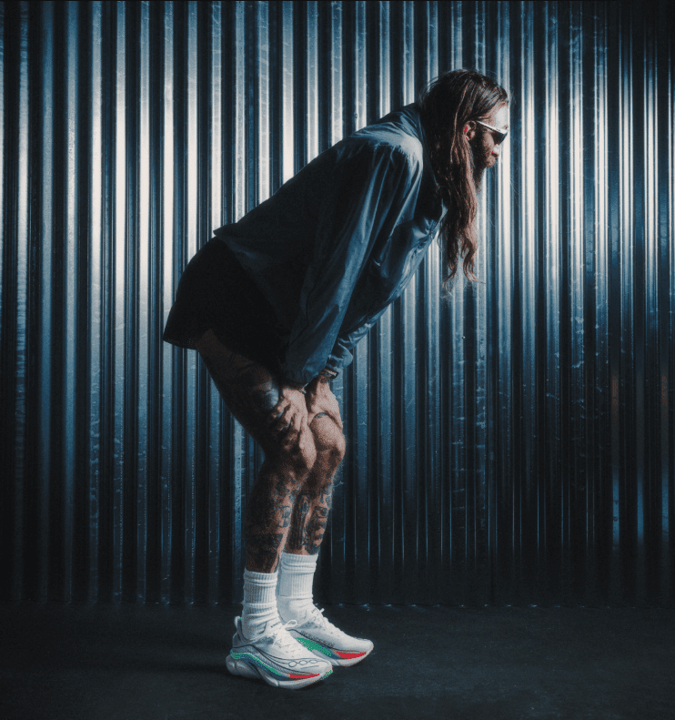 Person in athletic gear bending forward against metal backdrop