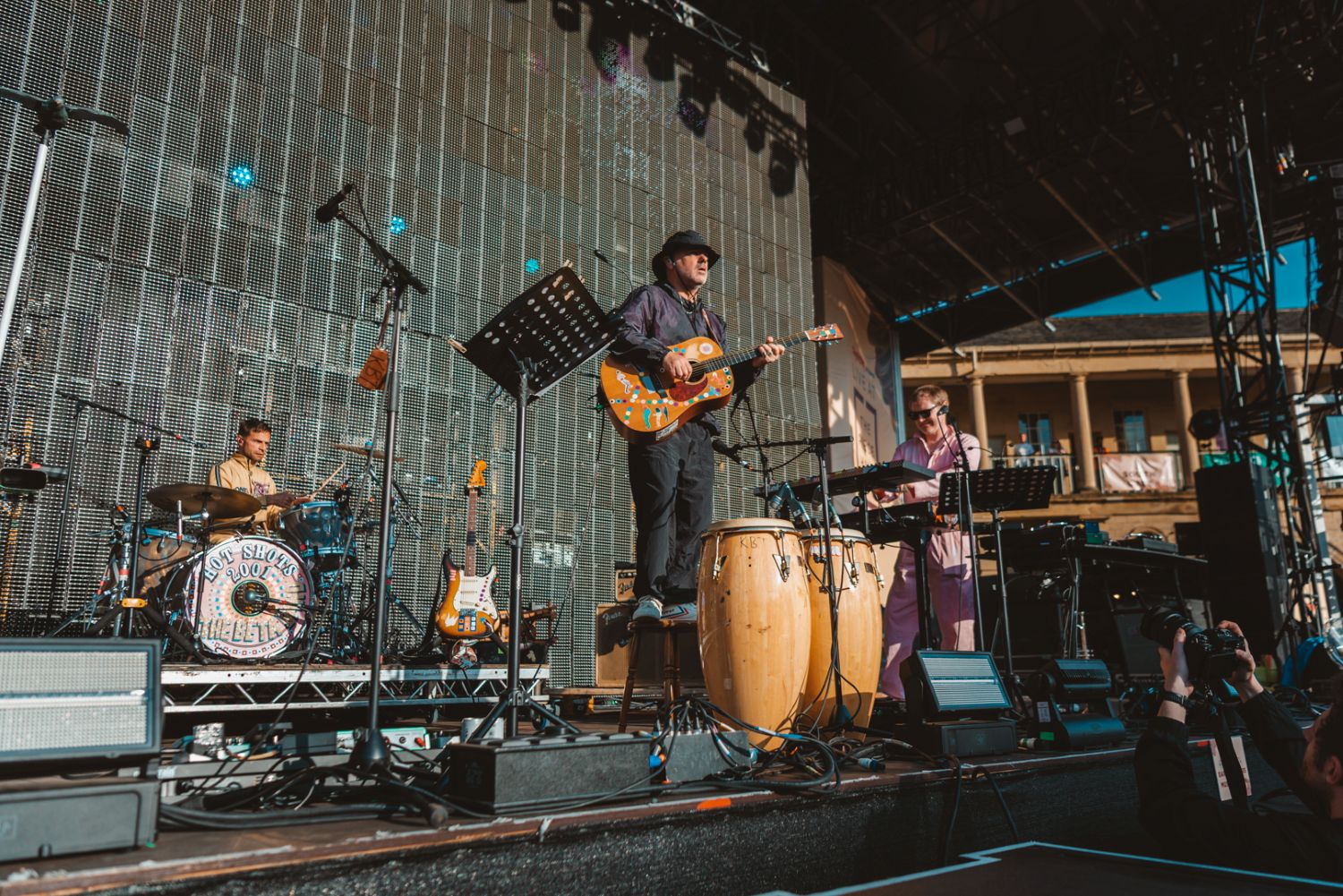 Outdoor concert with band playing on stage under blue sky