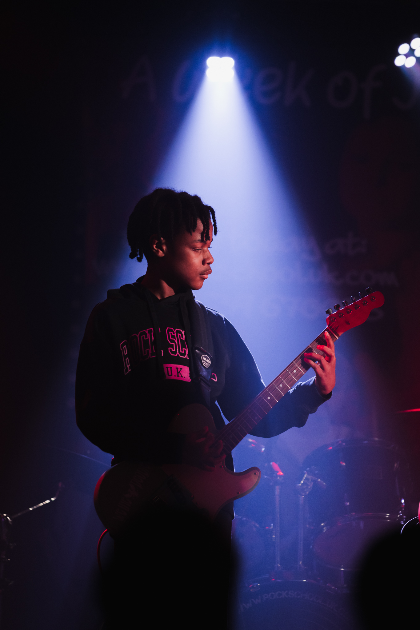 Guitarist on stage under spotlight with dim background