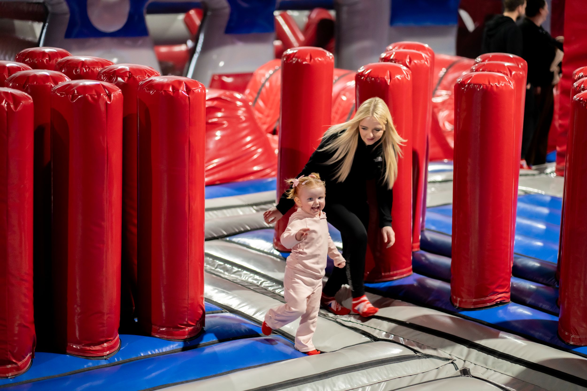 Child and woman enjoying inflatable obstacle course indoors