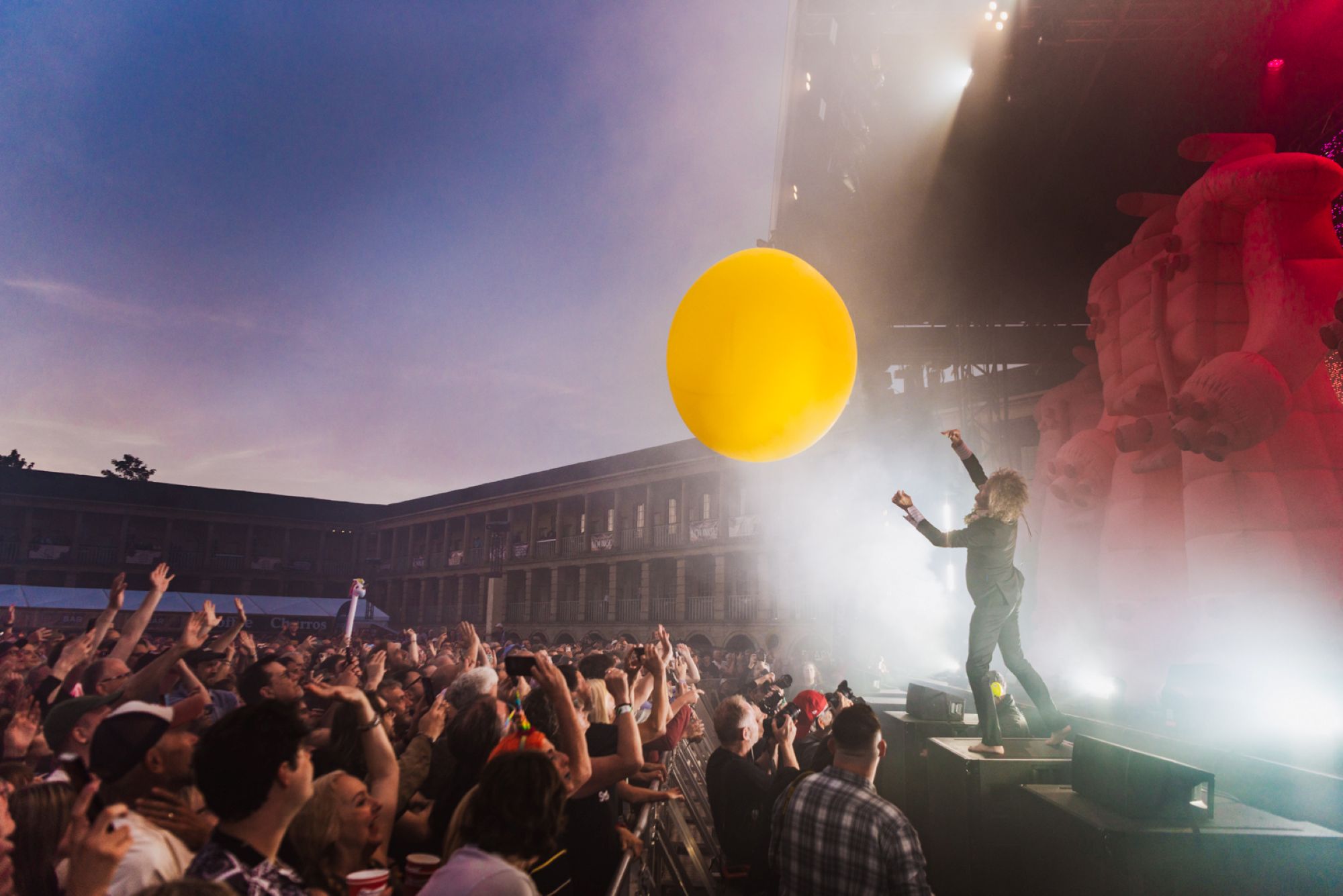 Crowd at outdoor concert with giant yellow balloon and stage lights