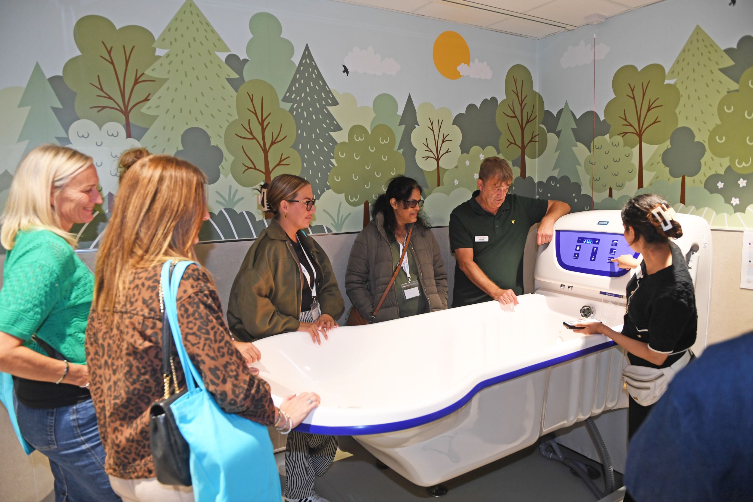 Group of people observing a demonstration in a modern bathroom showroom