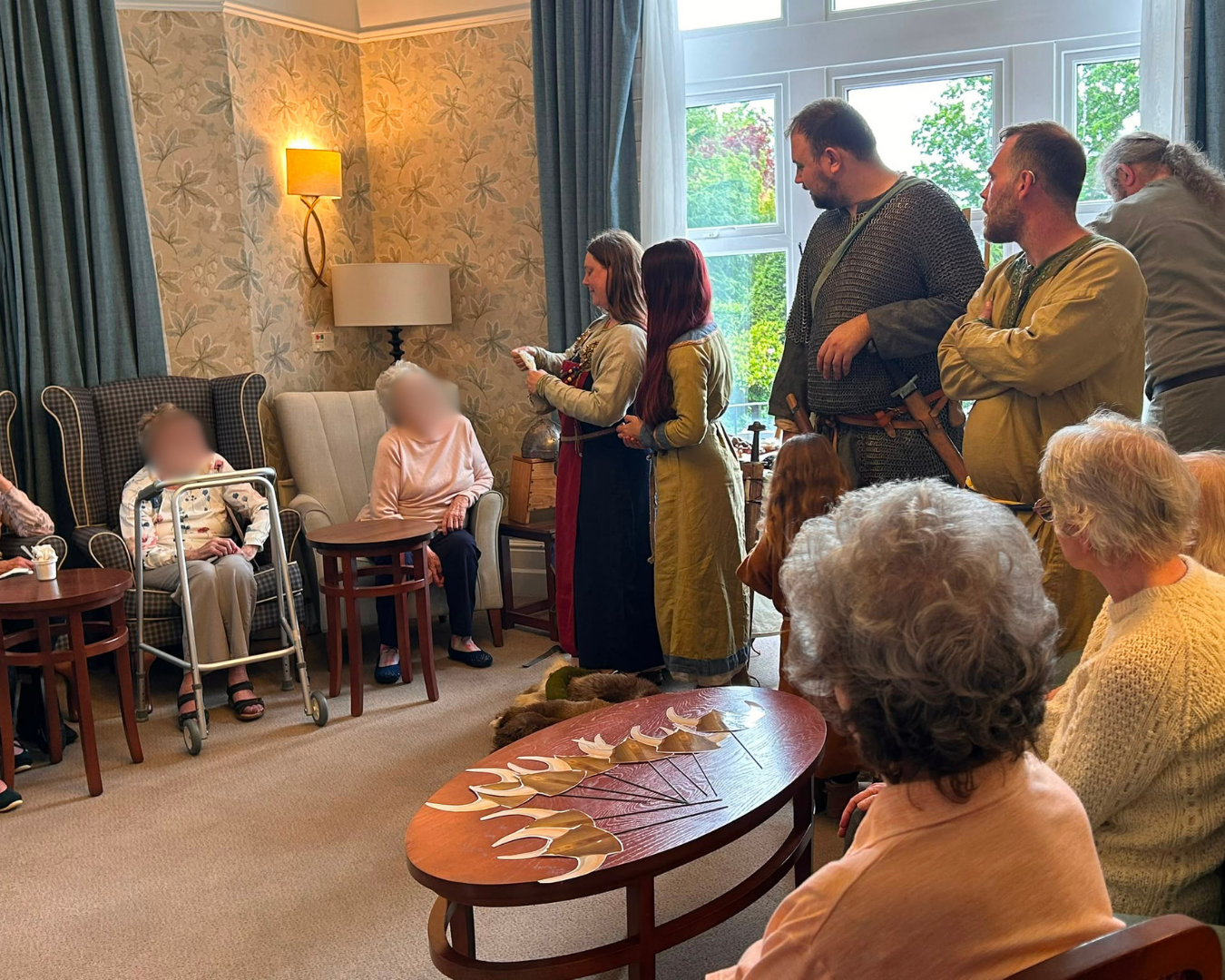 Group in historical costumes engaging with elderly in cozy room