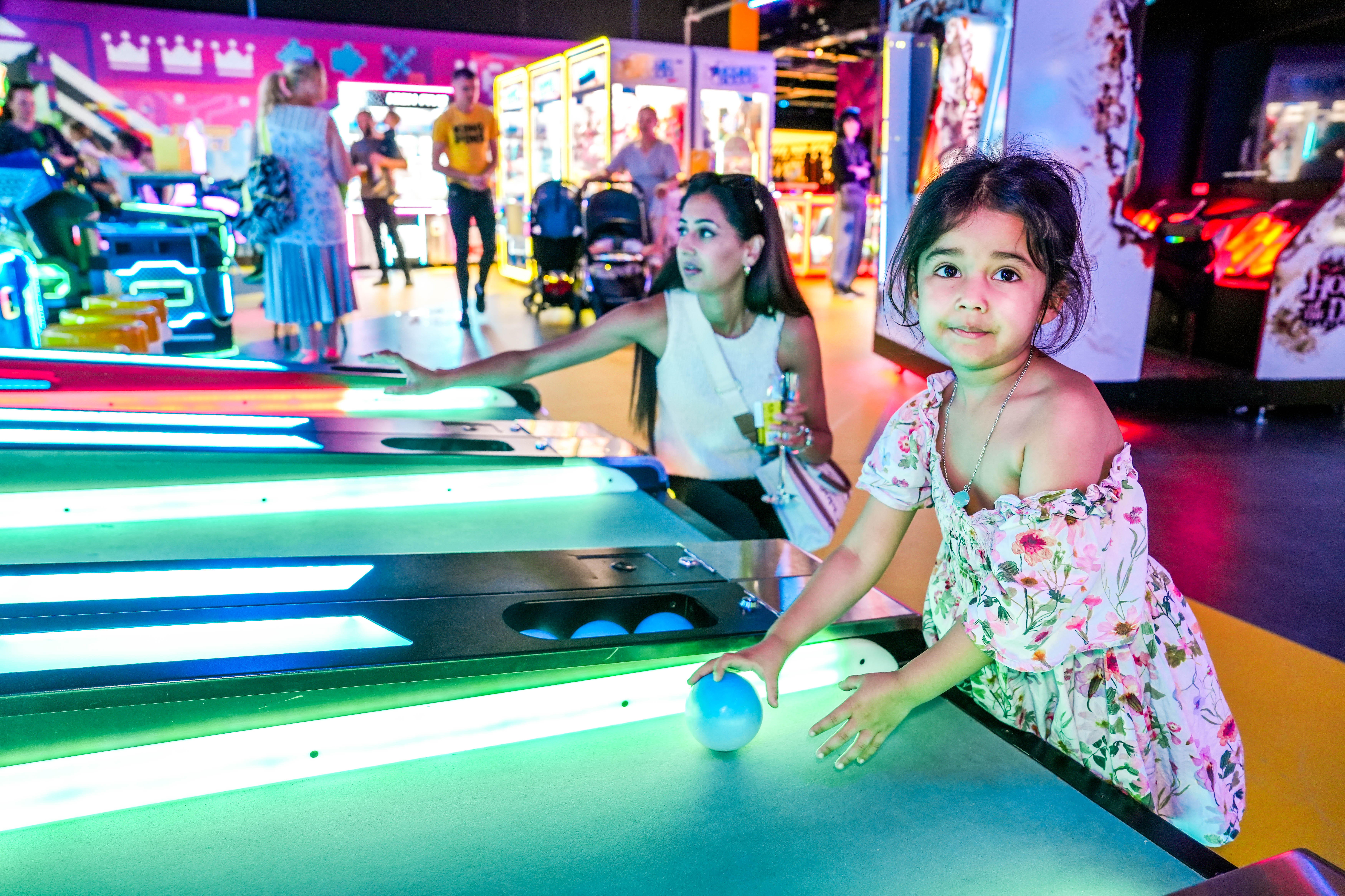 Child playing skee ball in a vibrant arcade setting