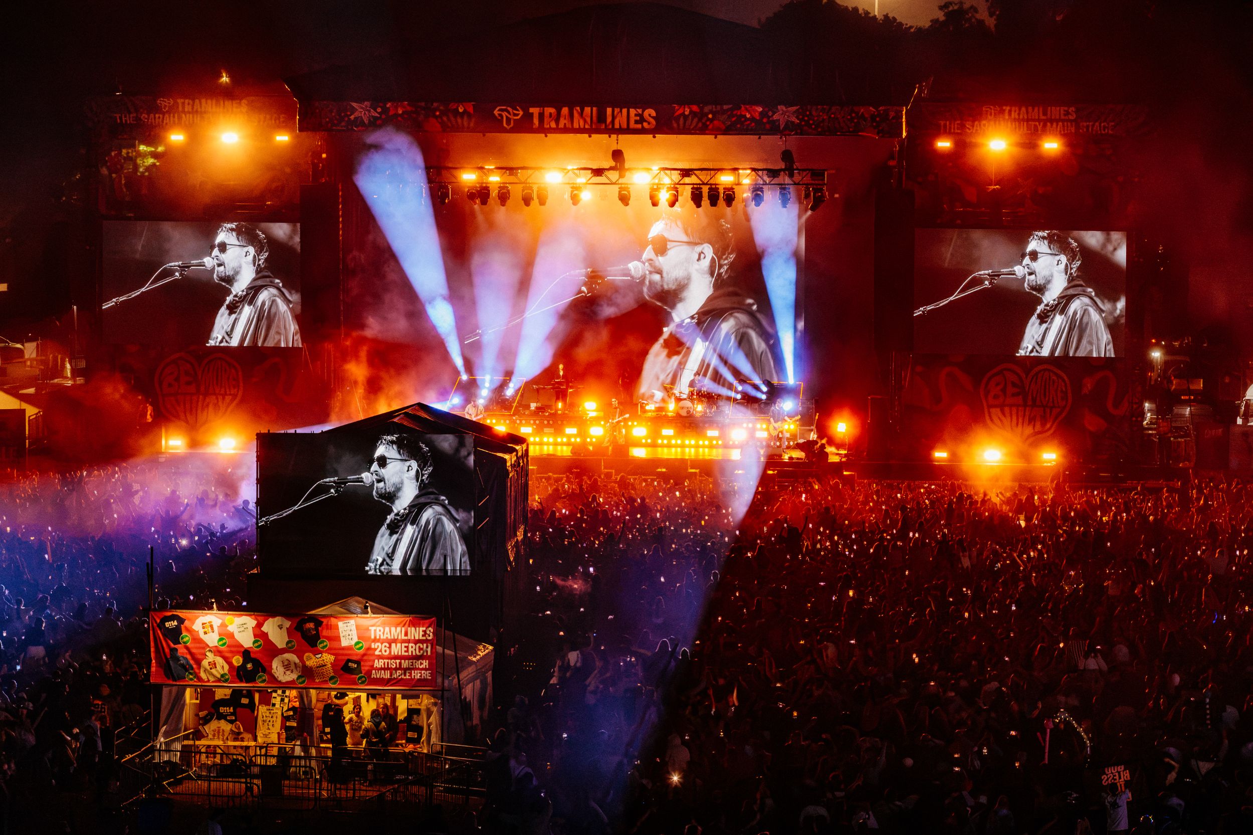Crowd at night concert with bright lights and large screens