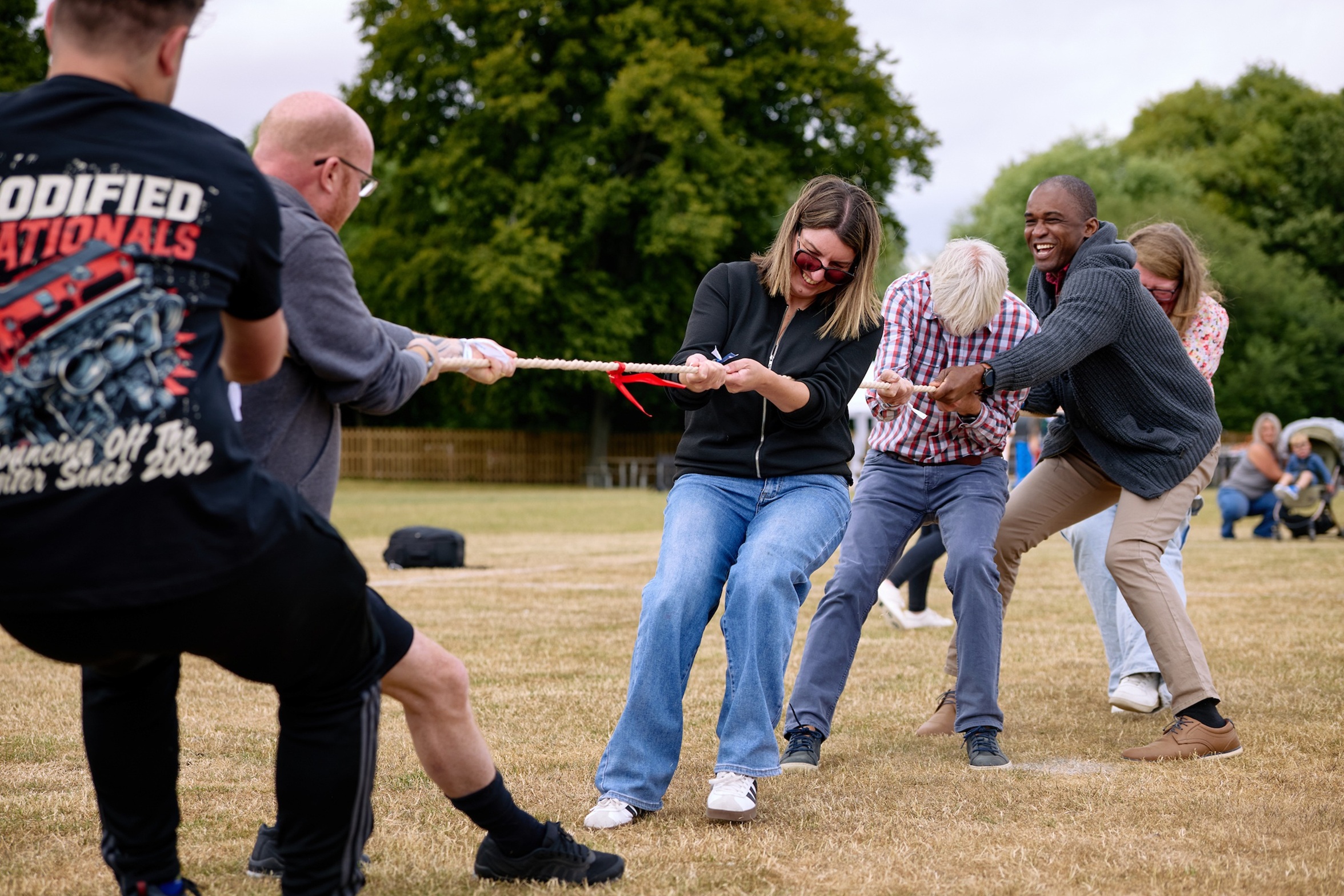 Group of people playing tug-of-war on a grassy field