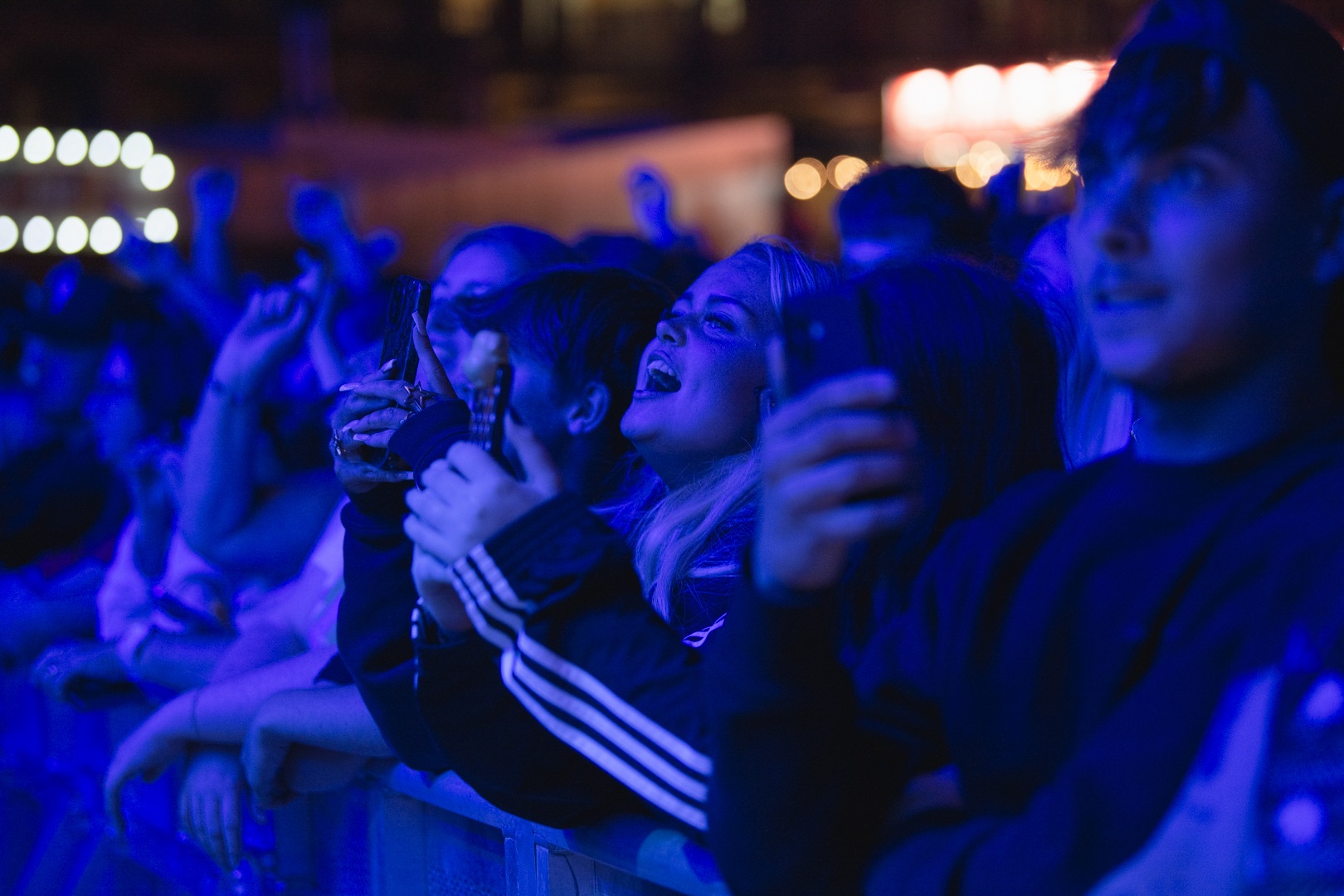 Crowd of enthusiastic concert-goers in blue lighting