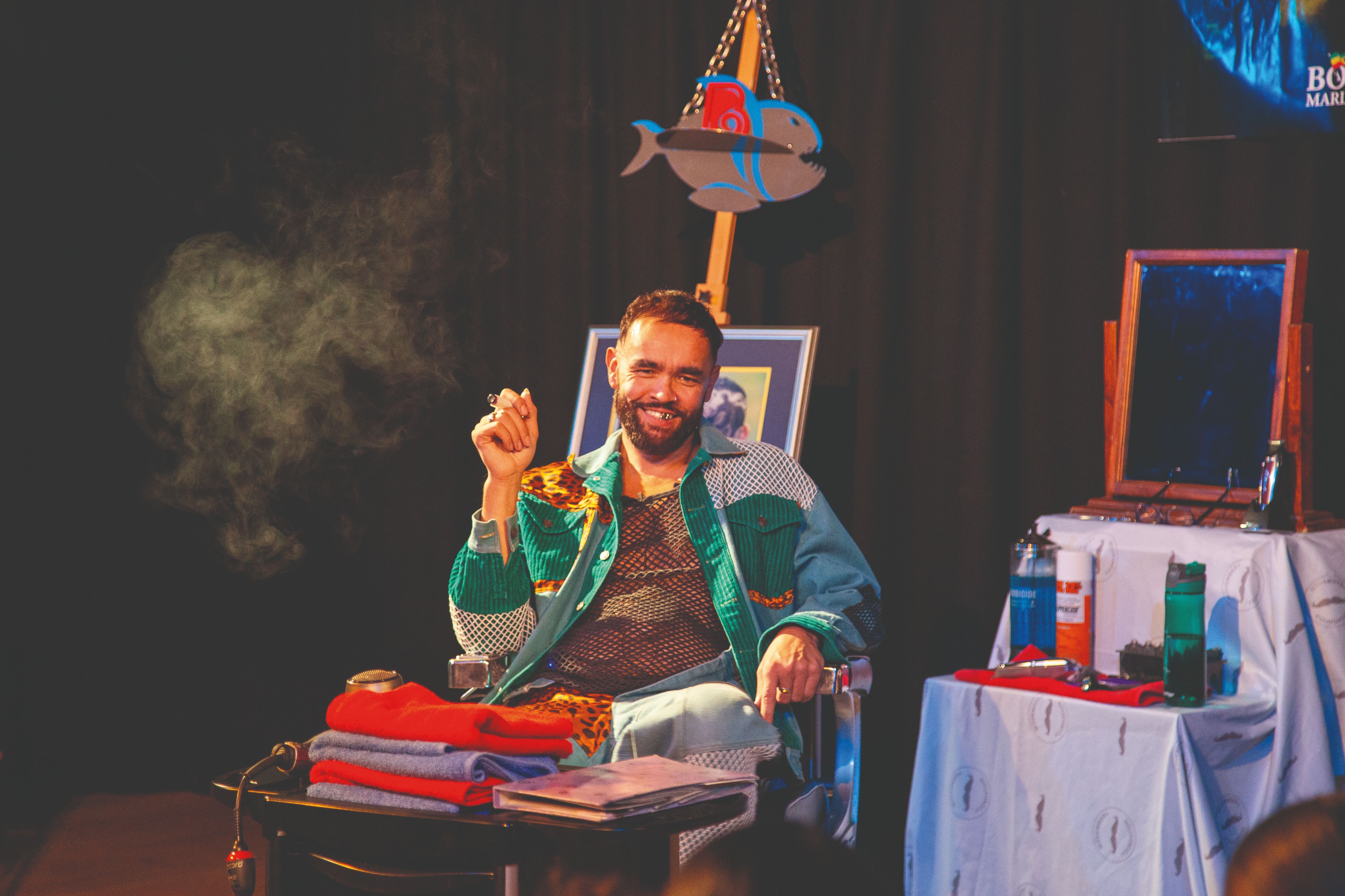 Man in colourful jacket smiling and smoking indoors