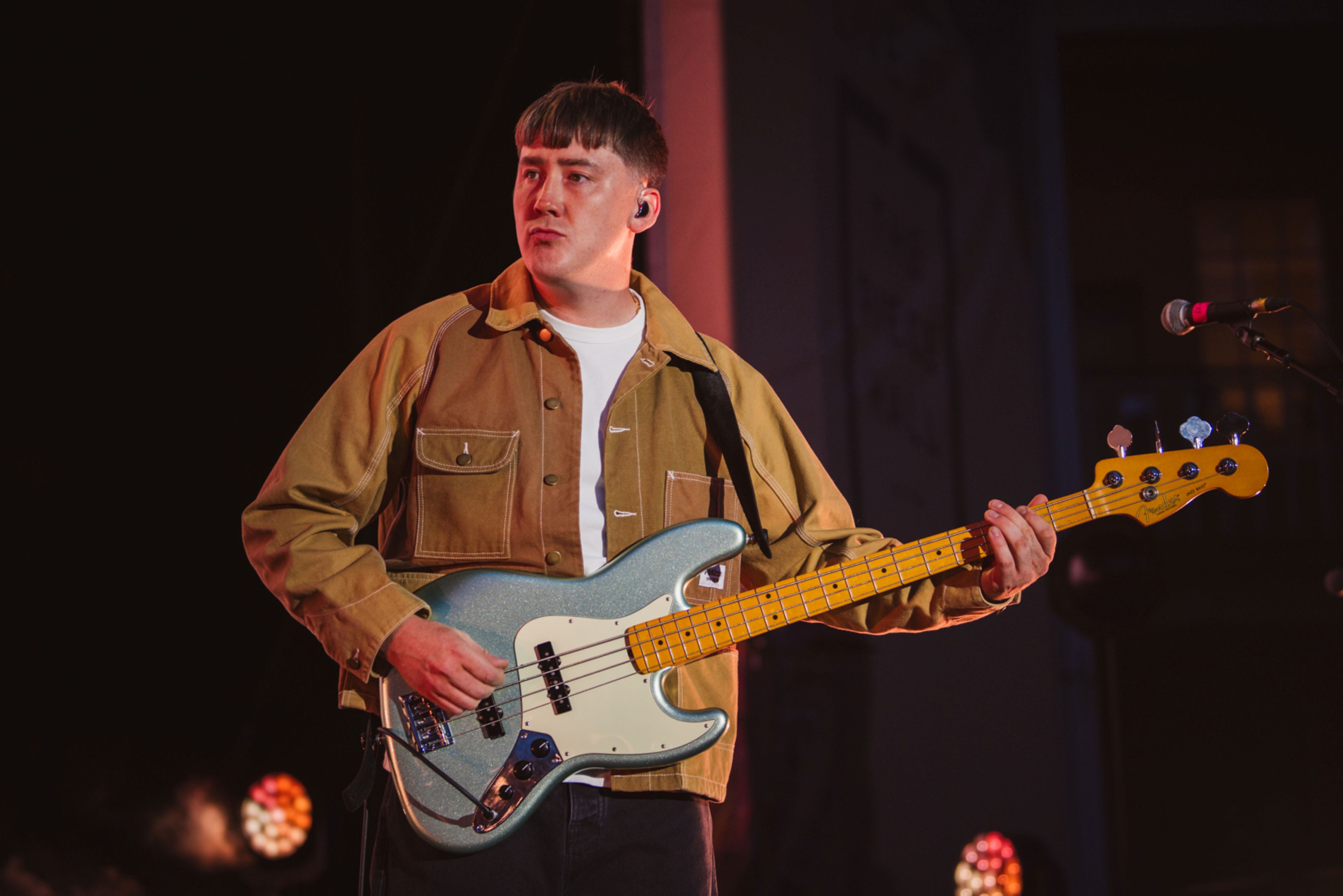 Musician playing electric bass guitar on stage with warm lighting