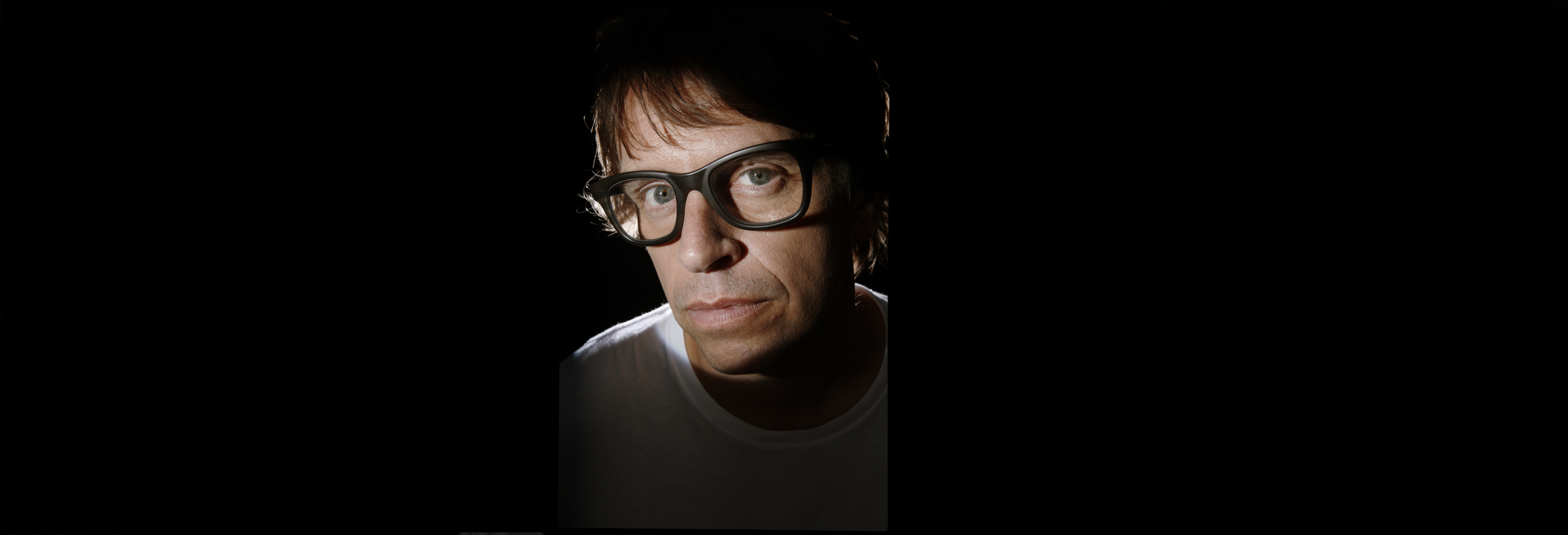 Close-up of a person wearing large black glasses with a serious expression