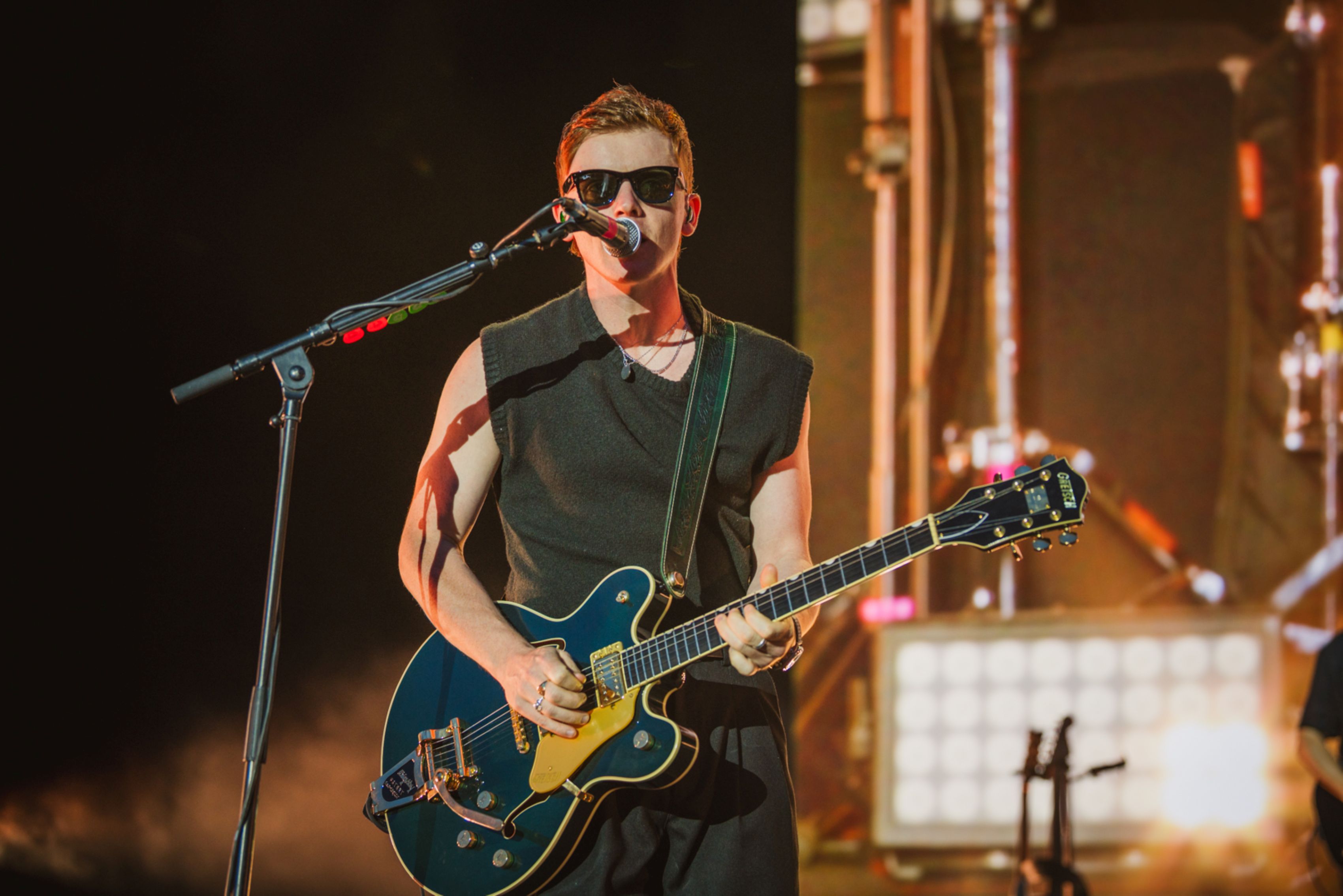 Musician in sunglasses playing electric guitar on stage