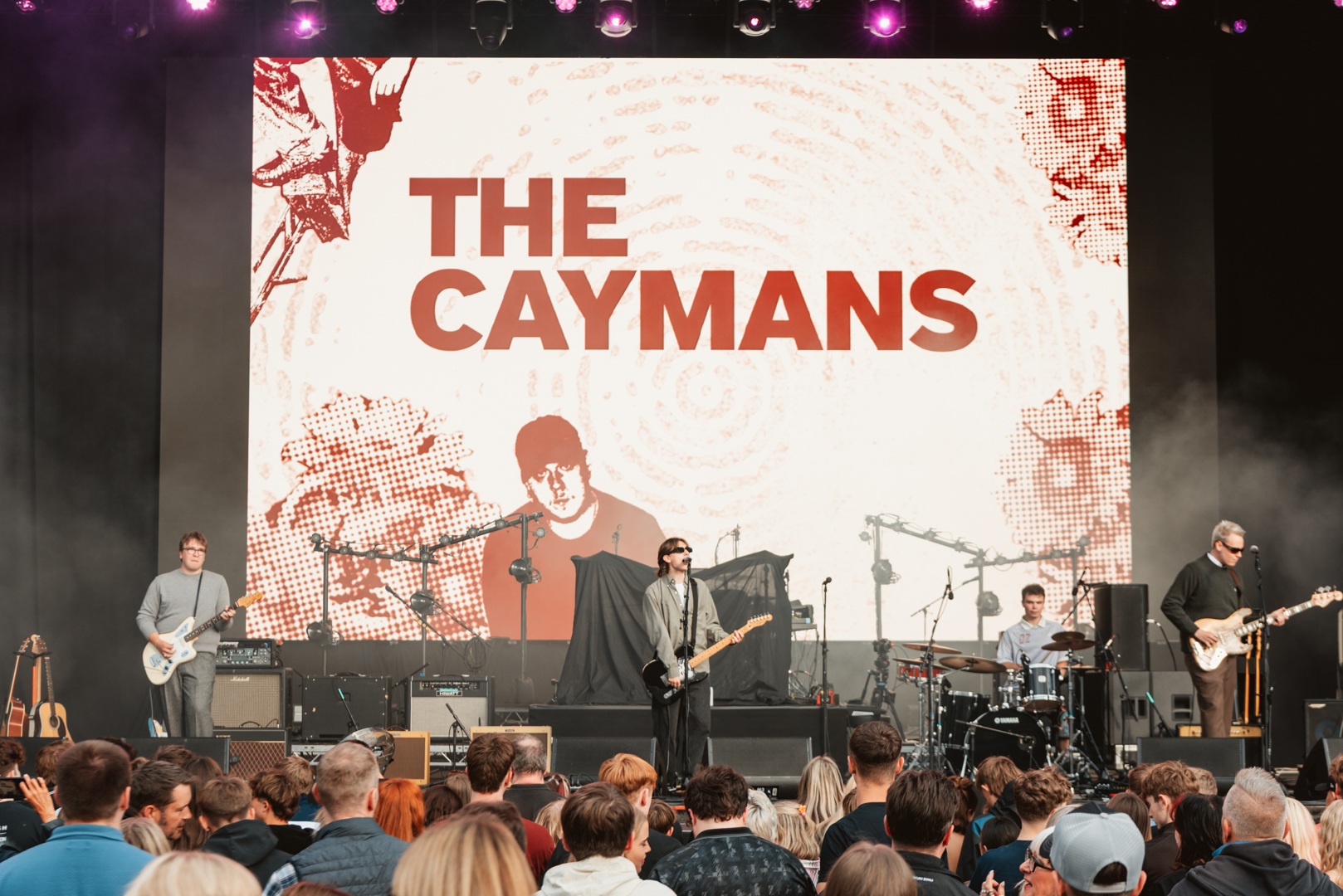 Live band performing on stage with large screen backdrop