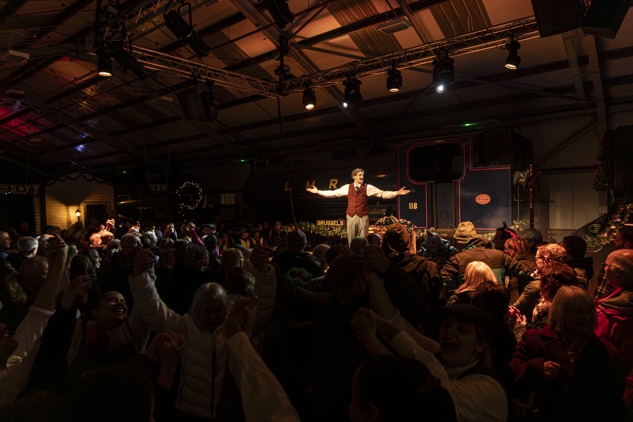 Festive crowd gathered around a performer in a railway museum